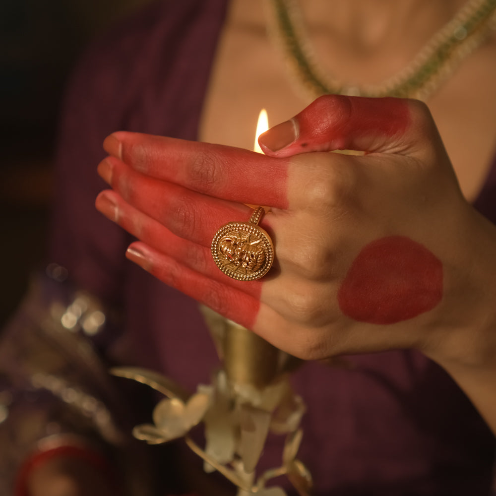 Gold ring with a Lakshmi goddess motif in a textured circular frame.