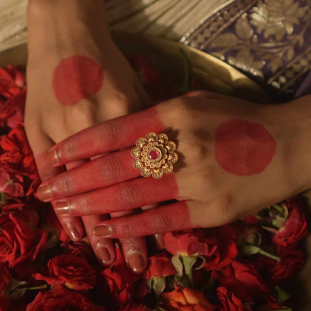 Gold-plated silver ring with a sunburst design and a central crimson gem.