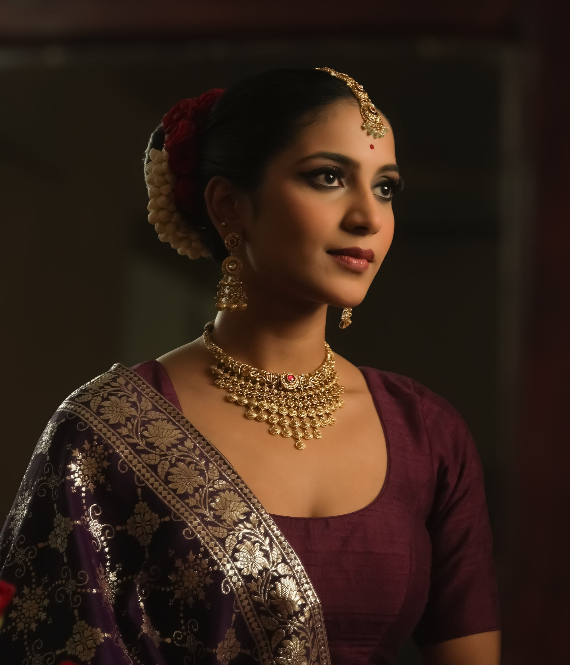 Gold necklace with dangling coin motifs and a central pendant with red gems.