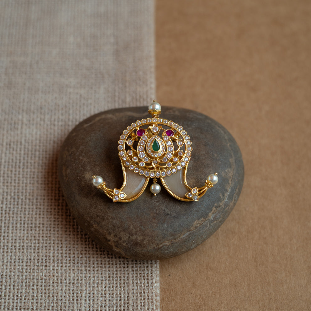 Temple-style gold pendant featuring goddess Lakshmi with CZ stones, pearls, and red-green spinal accents.