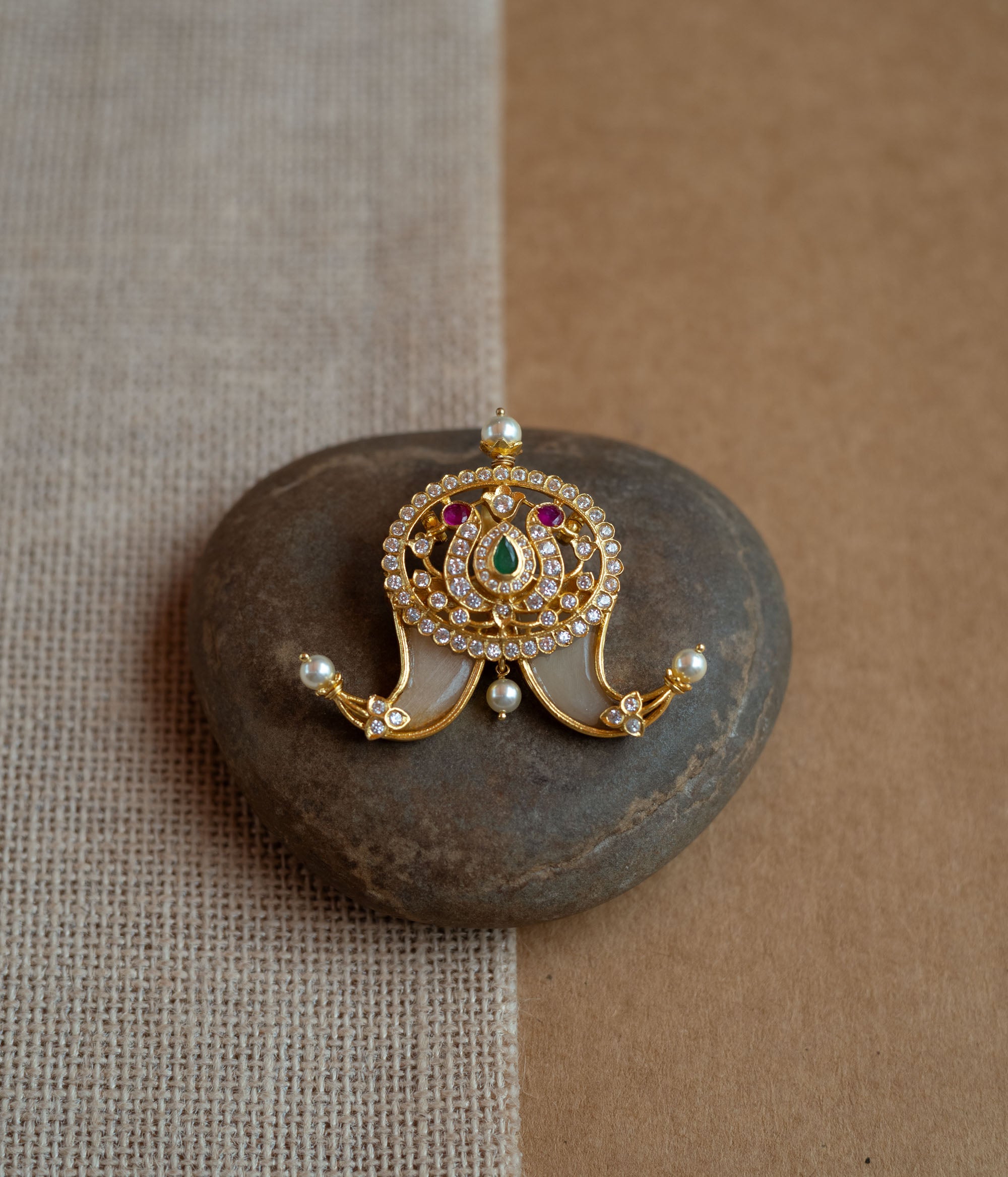 Temple-style gold pendant featuring goddess Lakshmi with CZ stones, pearls, and red-green spinal accents.