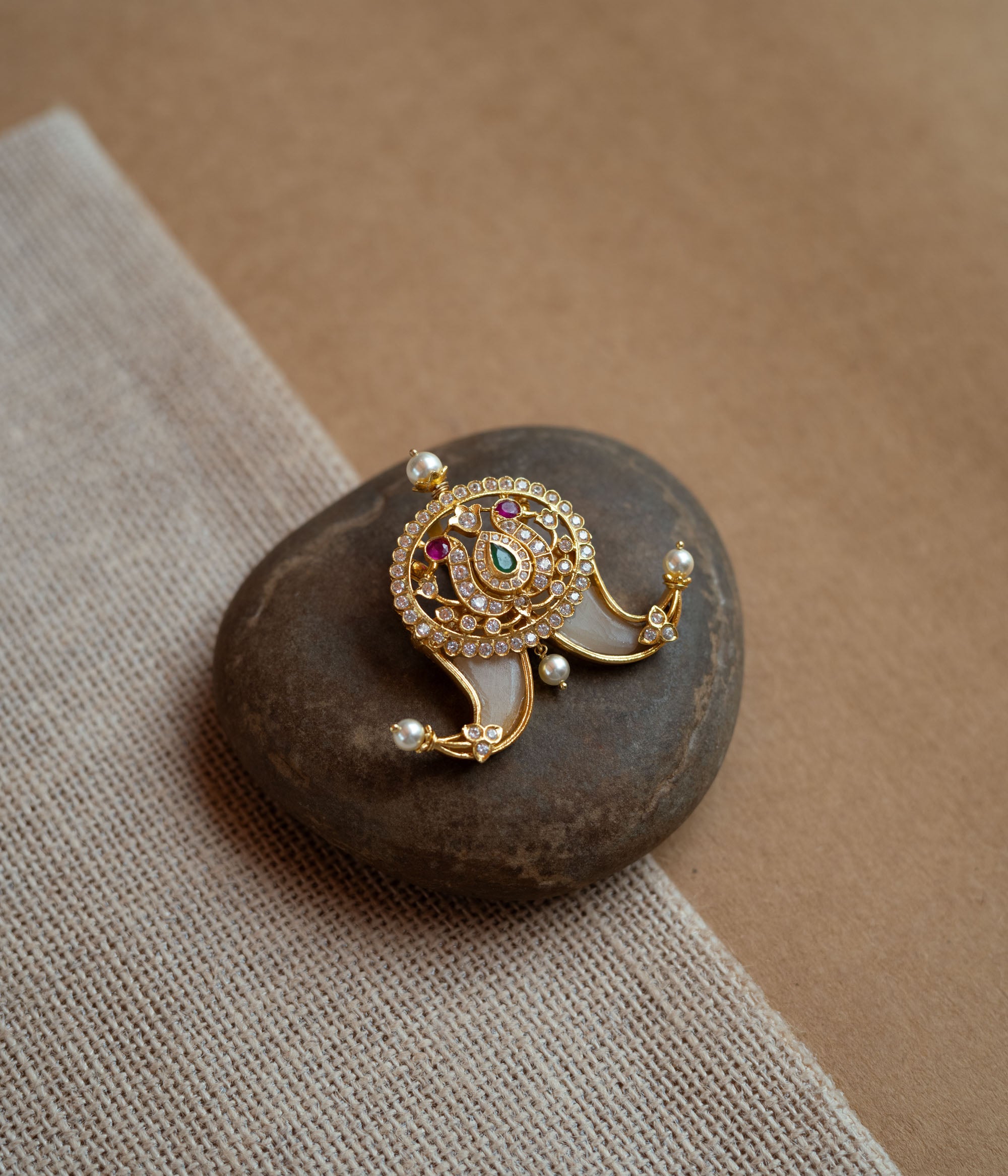 Temple-style gold pendant featuring goddess Lakshmi with CZ stones, pearls, and red-green spinal accents.
