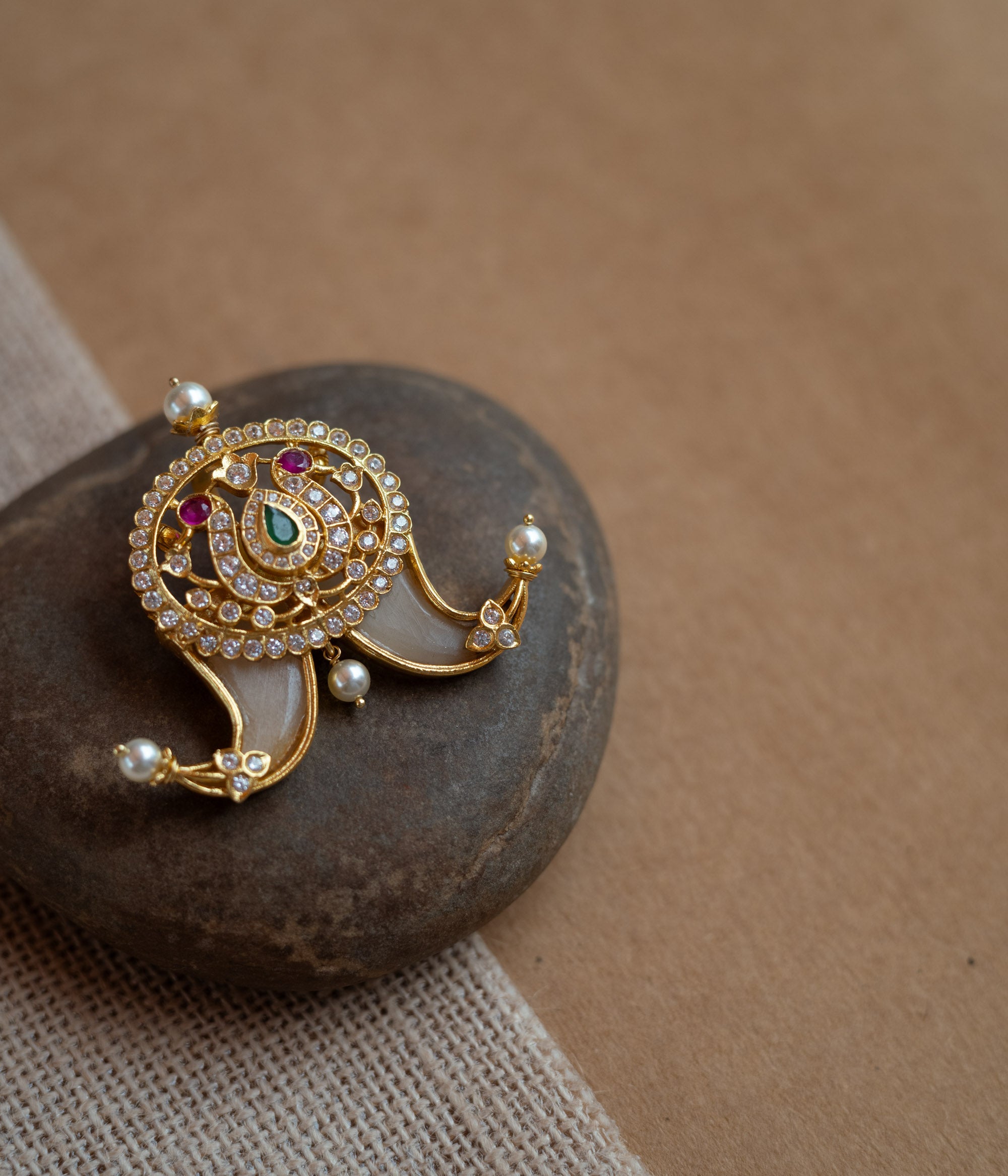 Temple-style gold pendant featuring goddess Lakshmi with CZ stones, pearls, and red-green spinal accents.