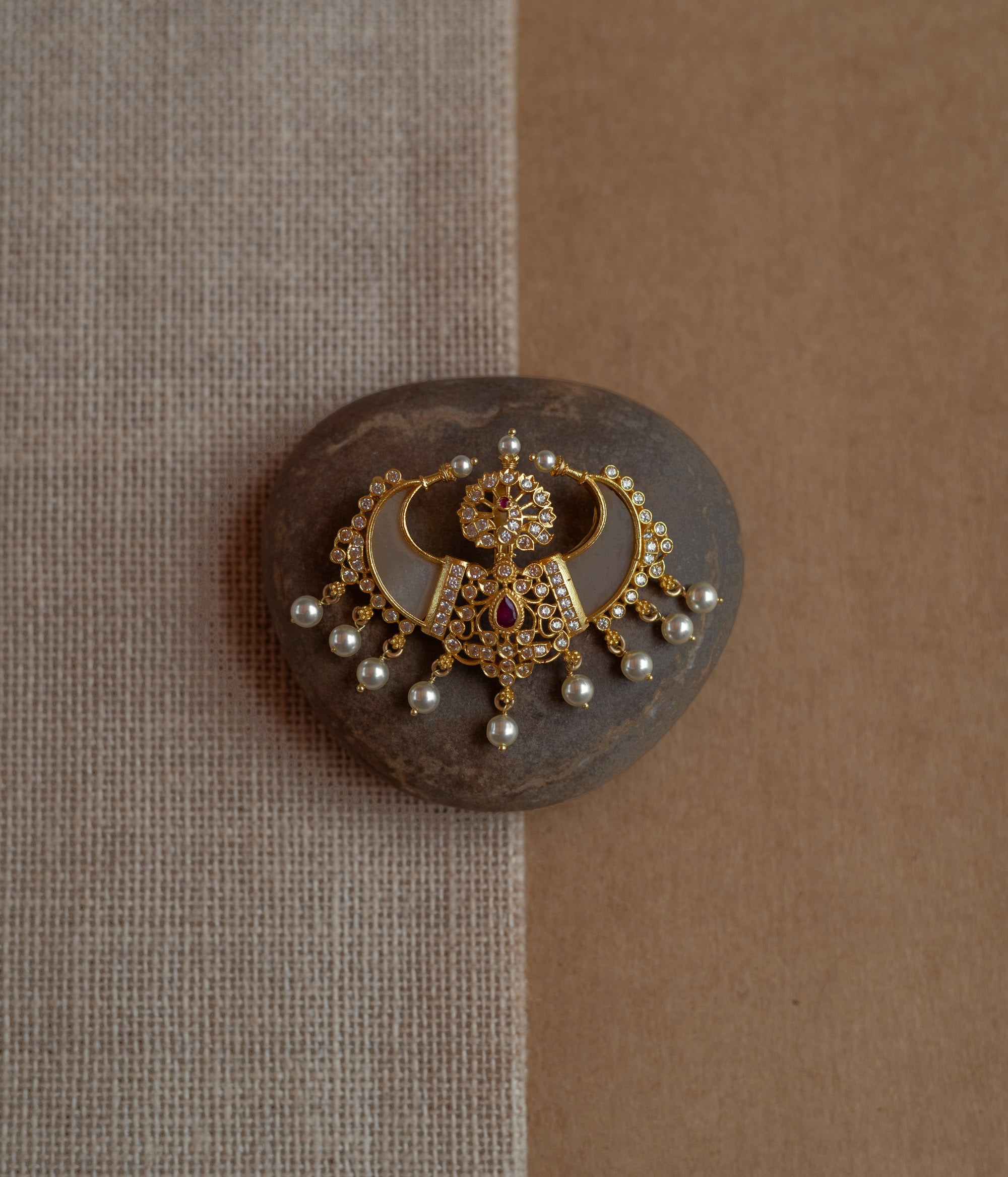 Gold pendant in twin crescent shape with CZ stones, pearls, and red spinal stone.