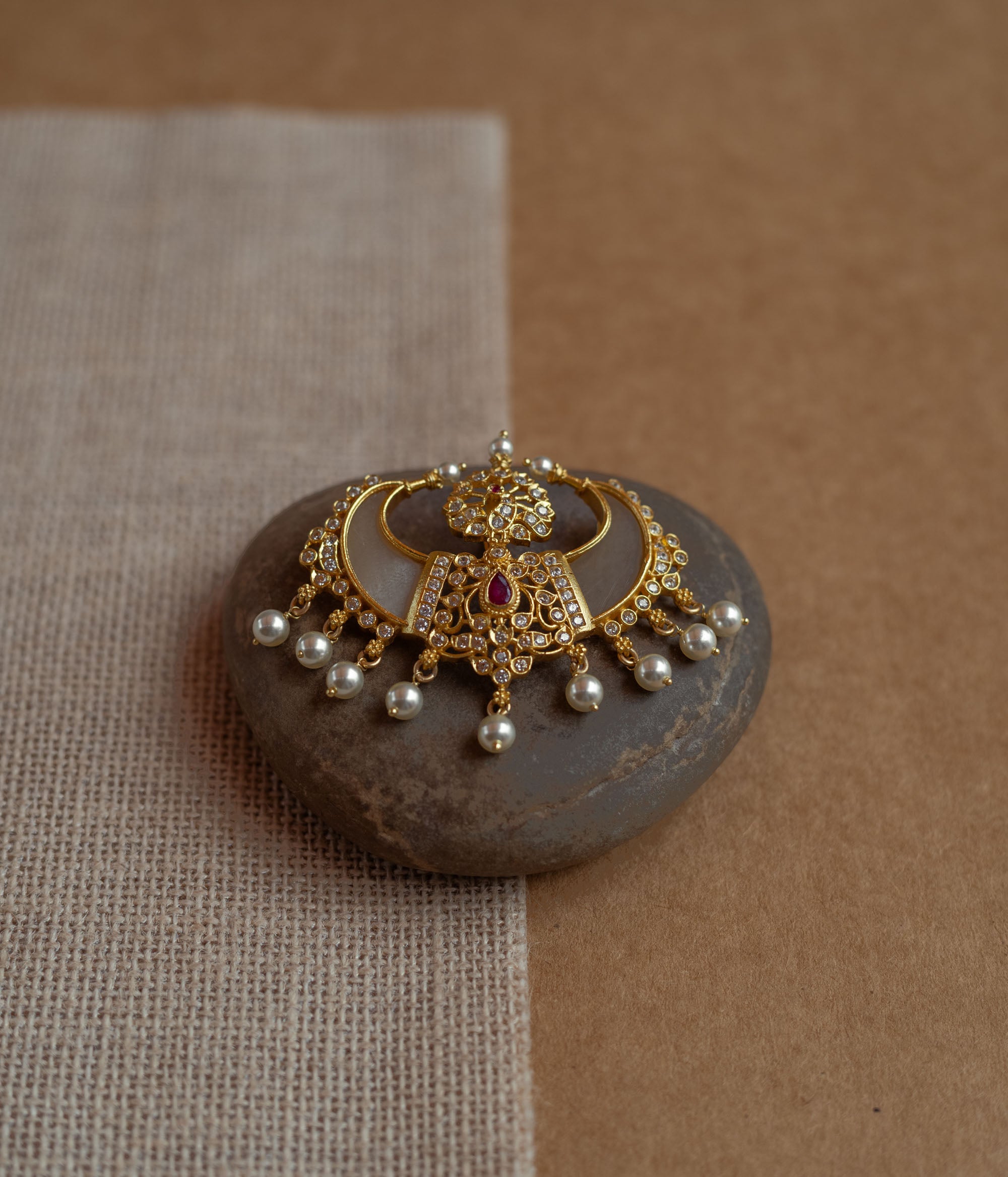 Gold pendant in twin crescent shape with CZ stones, pearls, and red spinal stone.
