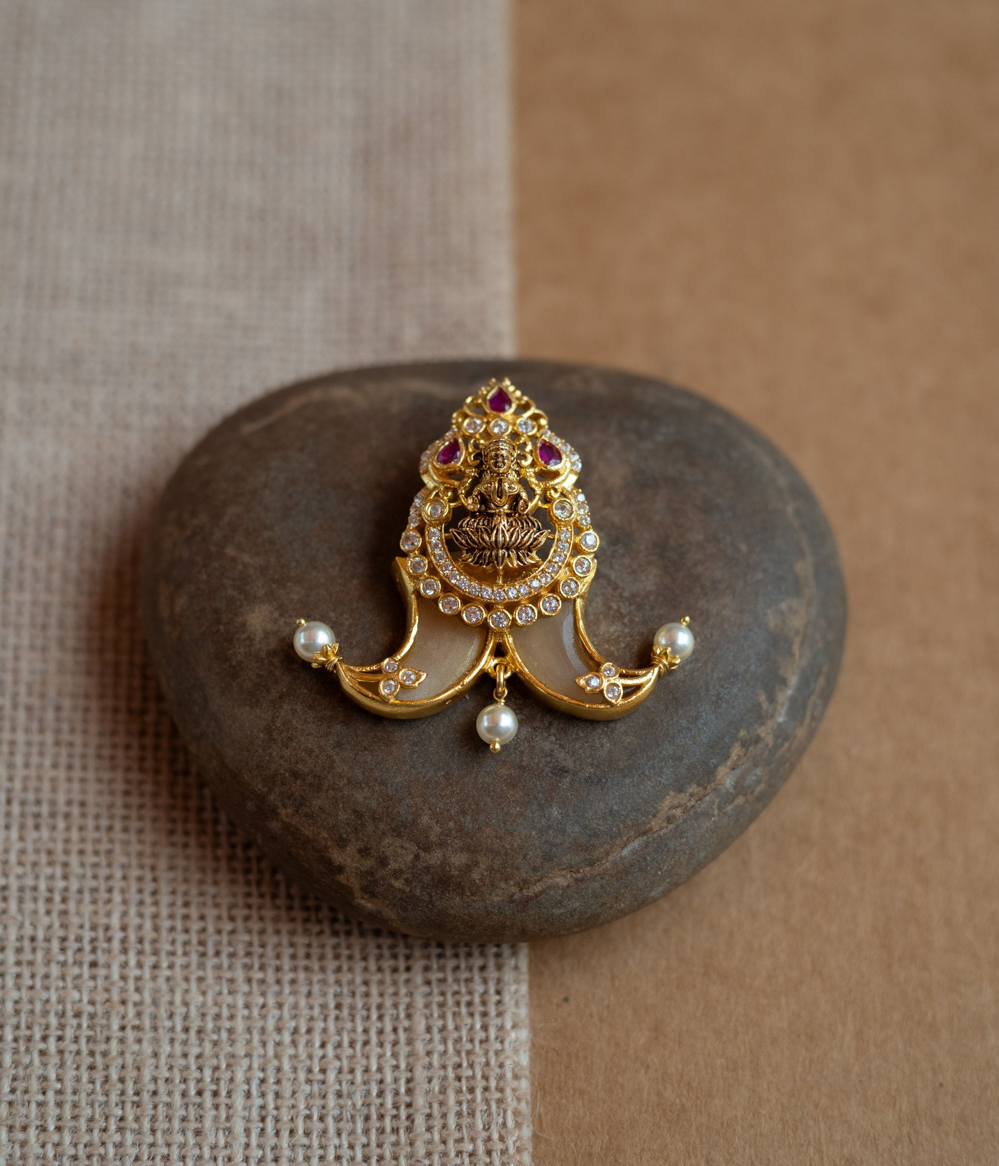 Gold amulet-shaped pendant with a goddess figure, red spinel, CZ stones, and pearls.
