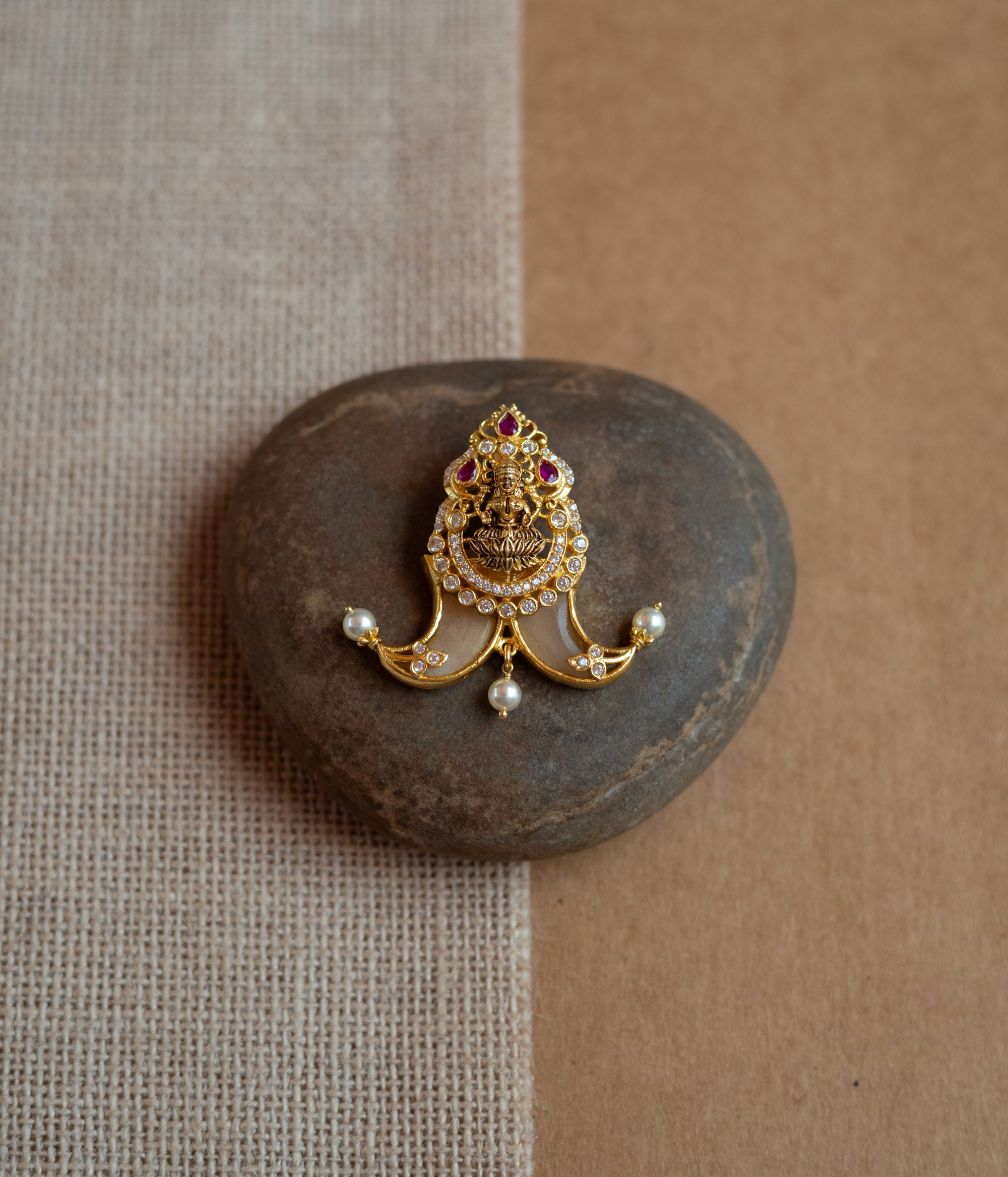 Gold amulet-shaped pendant with a goddess figure, red spinel, CZ stones, and pearls.