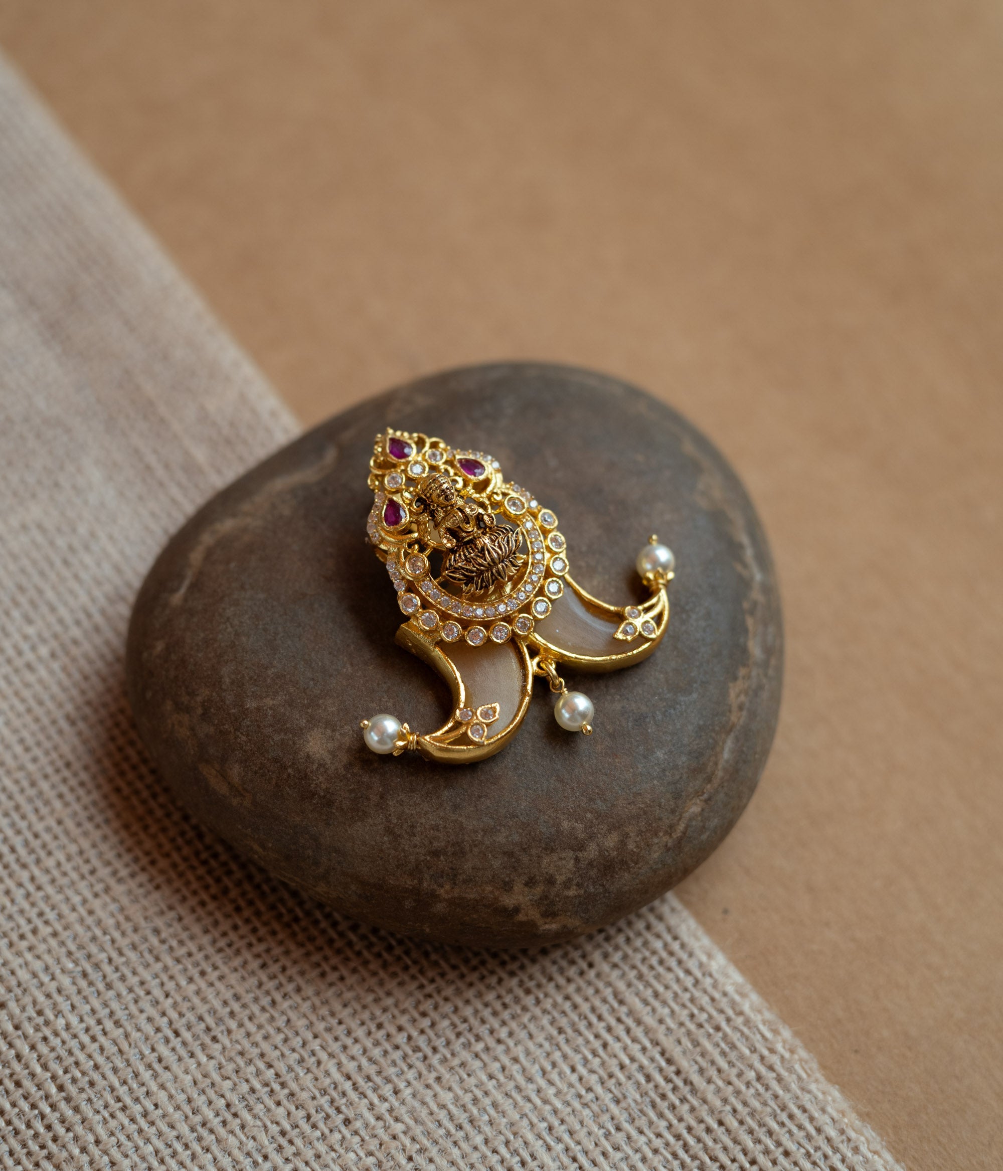 Gold amulet-shaped pendant with a goddess figure, red spinel, CZ stones, and pearls.