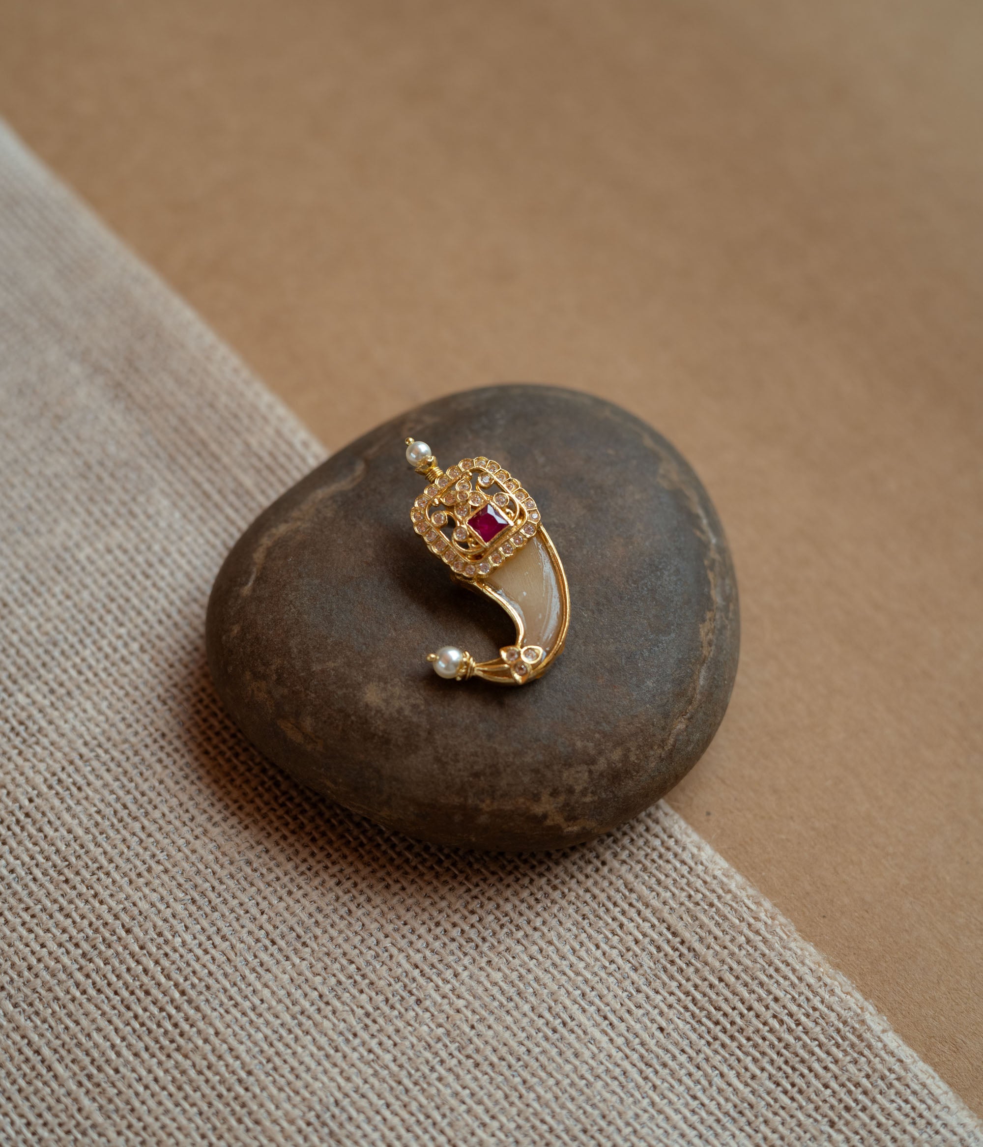 Gold amulet-shaped pendant with a prominent red spinel stone, CZ stones, and pearl drops.