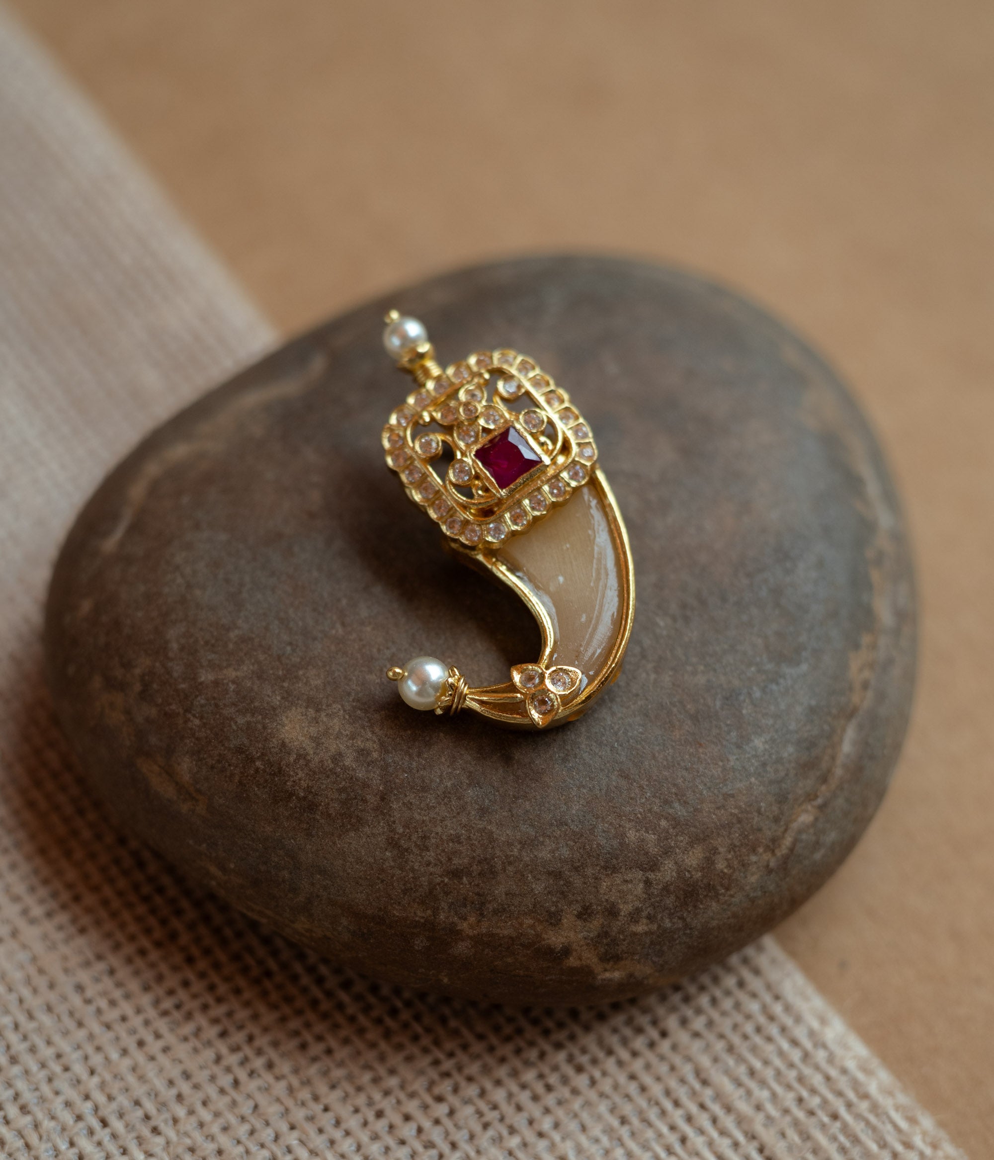 Gold amulet-shaped pendant with a prominent red spinel stone, CZ stones, and pearl drops.