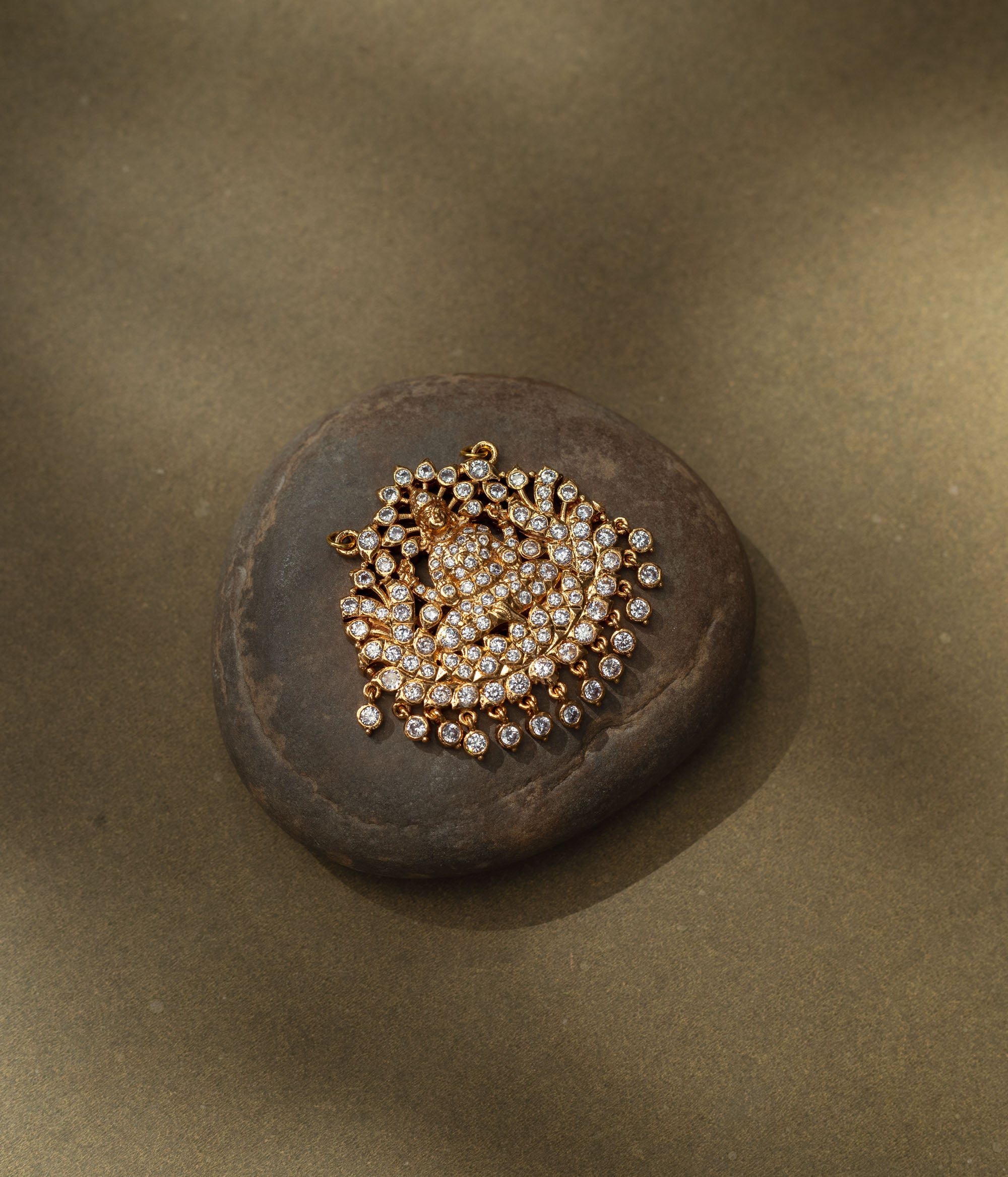 Gold pendant with goddess figure and CZ stones in a radiant circular design from Stone Collection.