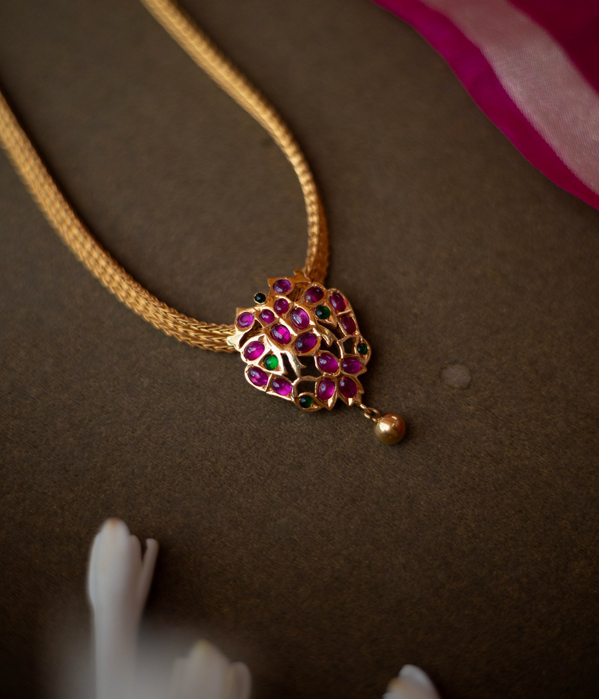 Gold-toned necklace with peacock-inspired pendant featuring red and green spinal stones.