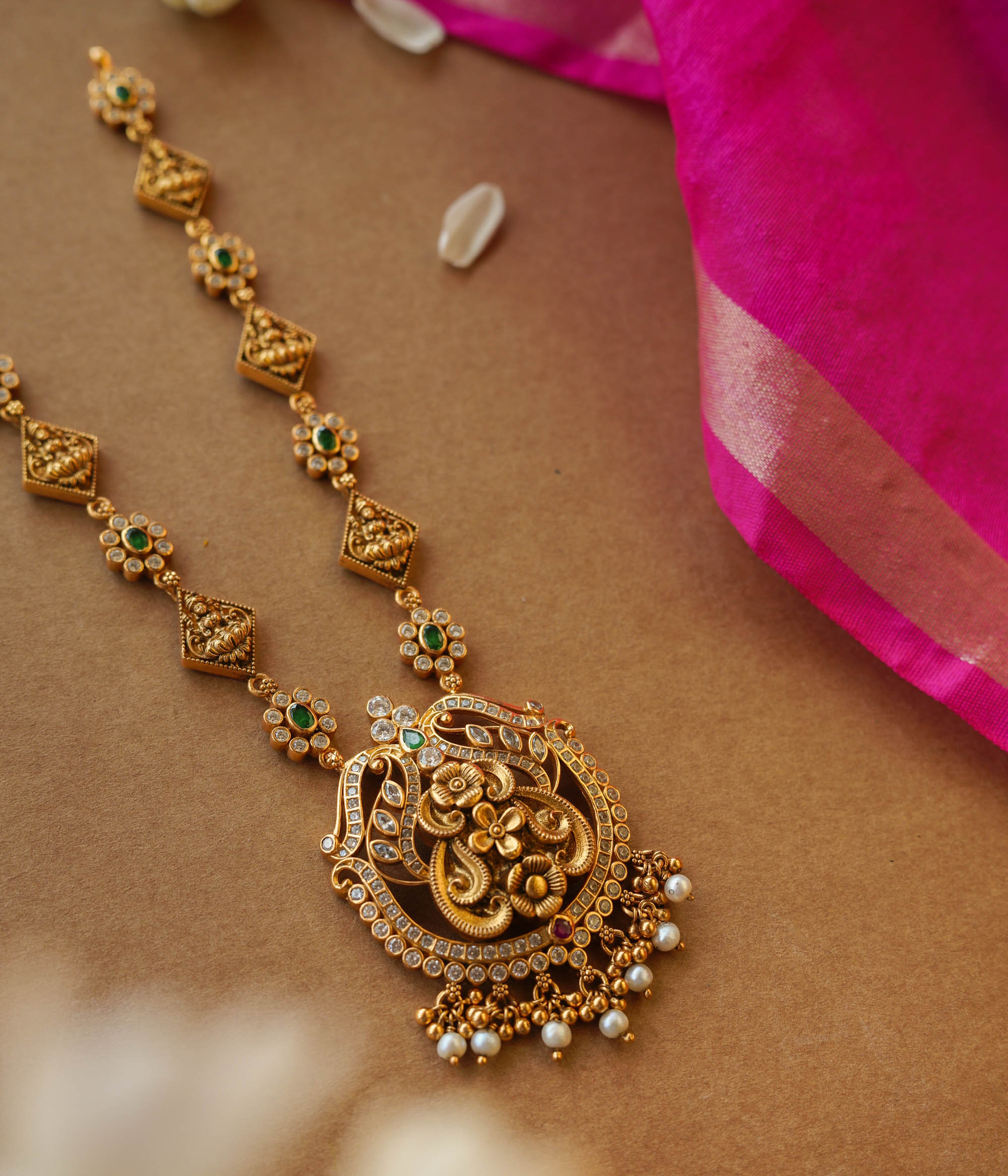 Temple-inspired gold necklace with peacock motif and Swarovski, red, and green spinal stones.