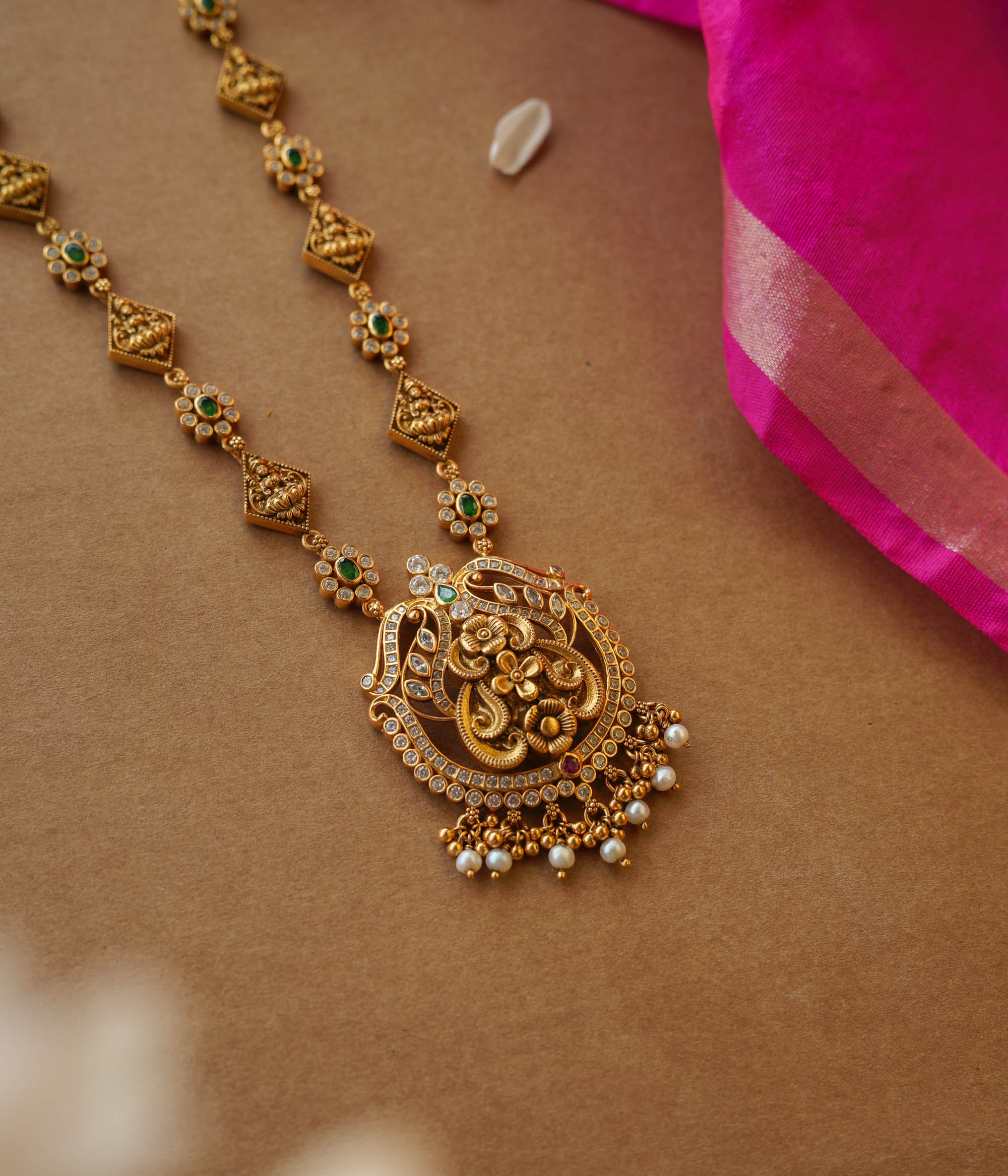 Temple-inspired gold necklace with peacock motif and Swarovski, red, and green spinal stones.