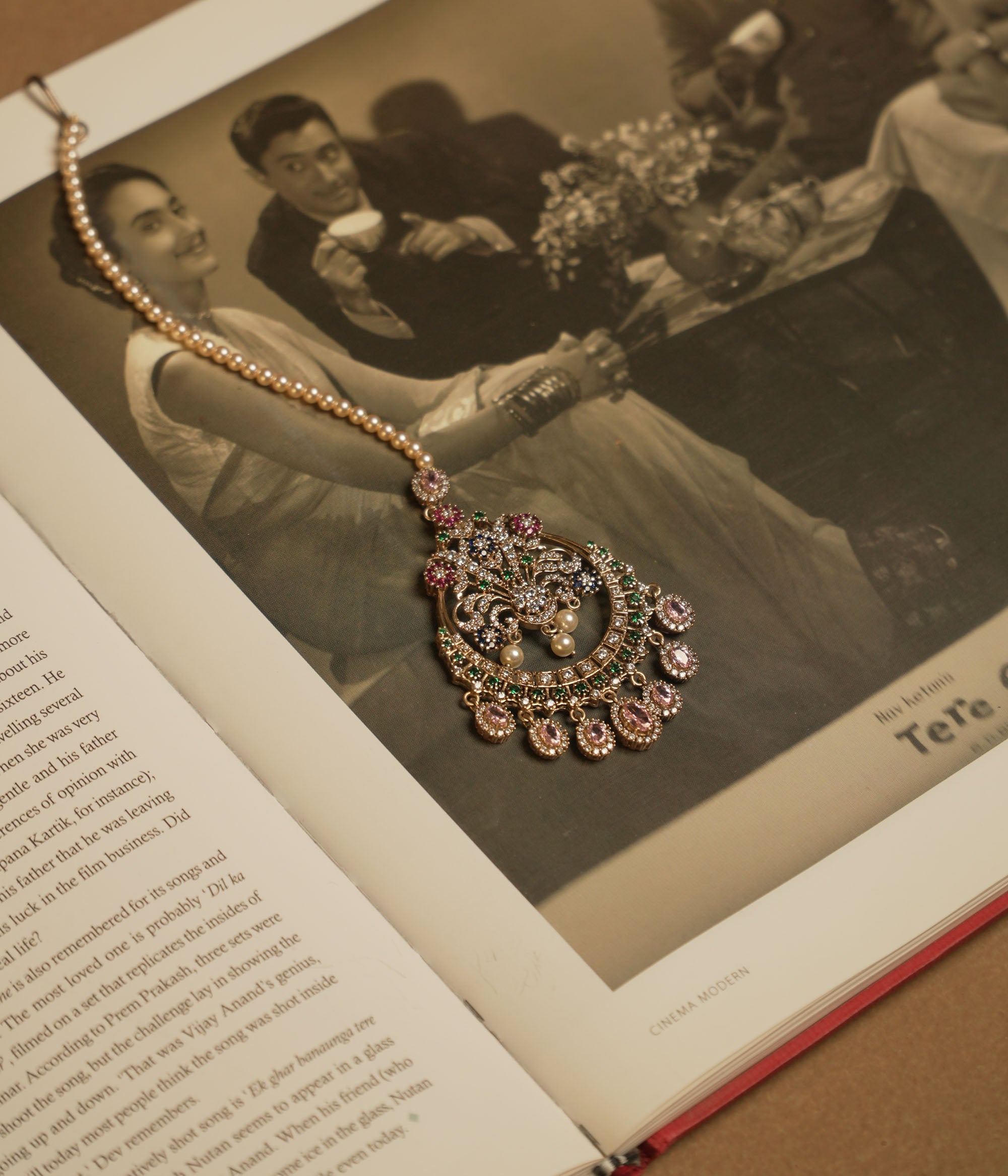 Traditional tikka with Swarovski stones, pink Kundan, and pearl drops in a floral crescent design.