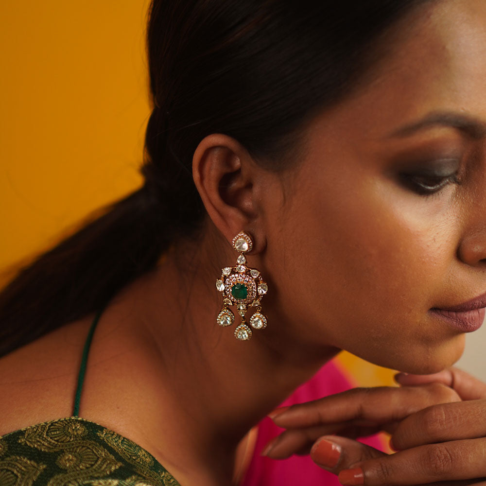 The Sadabahar earrings, meticulously crafted in gold-plated silver, showcase a delicate interplay of polki, green spinel, and CZ stones. Infused with vintage charm, this exquisite design radiates timeless elegance.