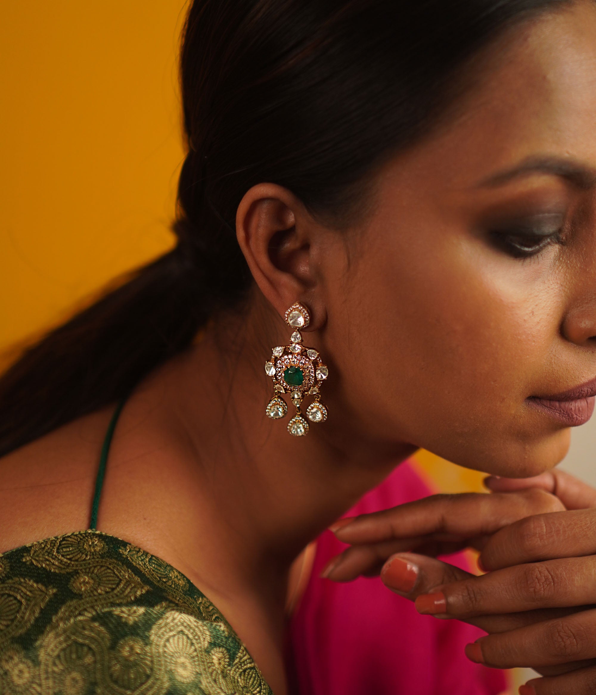 The Sadabahar earrings, meticulously crafted in gold-plated silver, showcase a delicate interplay of polki, green spinel, and CZ stones. Infused with vintage charm, this exquisite design radiates timeless elegance.
