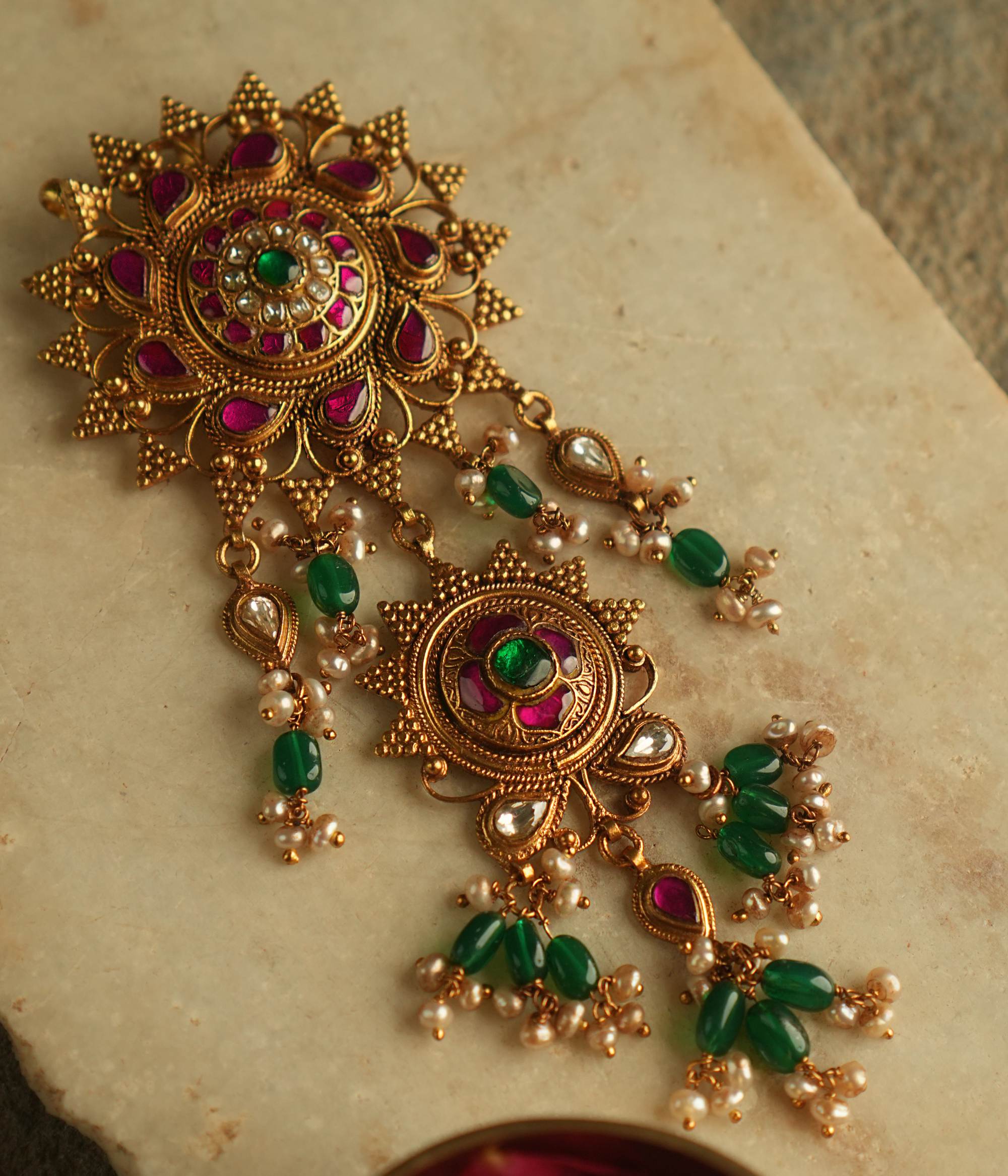 Blending traditional elegance with contemporary allure, this gold-plated pendant is adorned with red, green, and white Kundan stones, accented by luminous pearls for a timeless and sophisticated look.