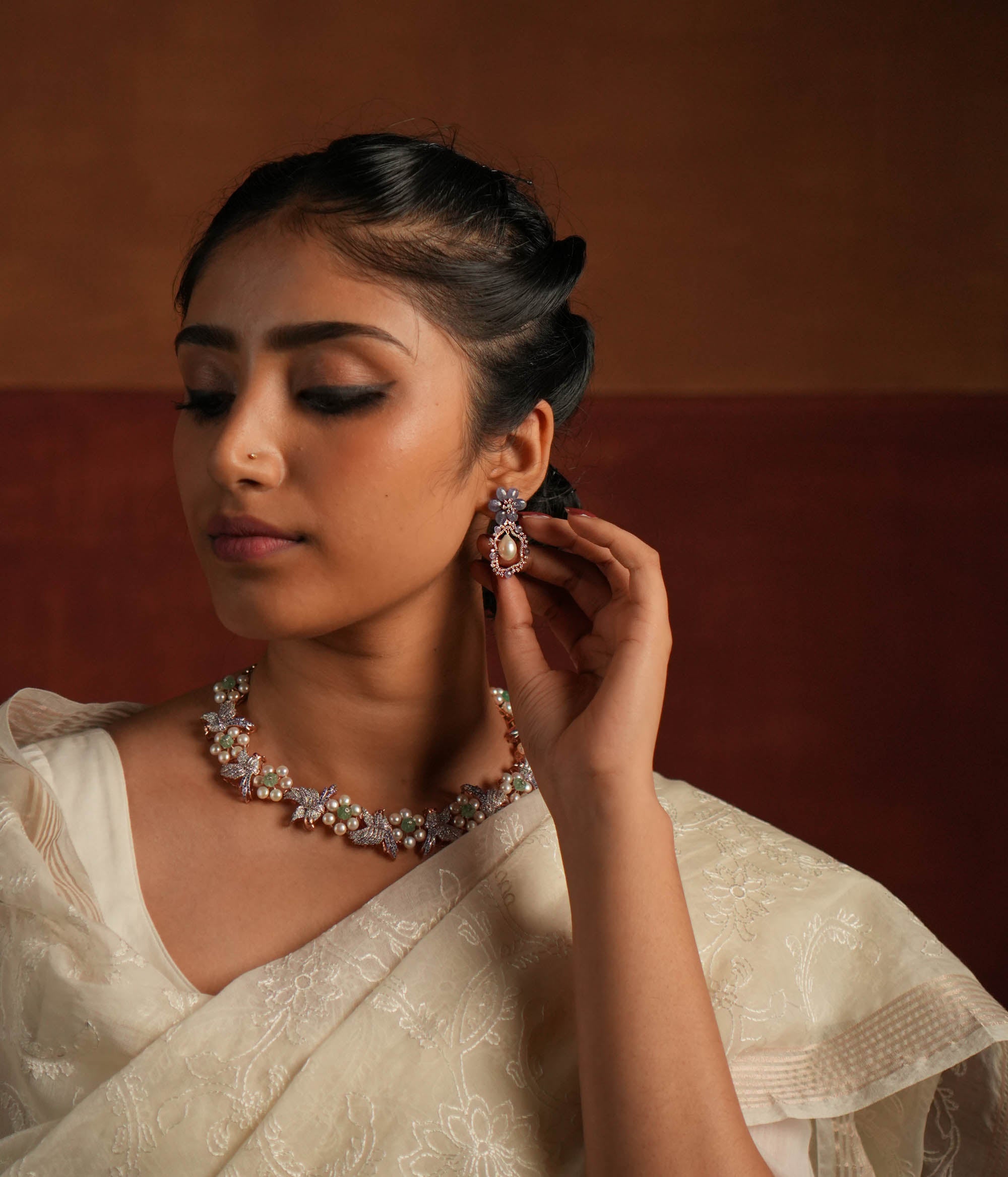 Exquisite drop earrings featuring a floral-shaped stud crafted from stunning tanzanite stones. The drop showcases an elegant asymmetrical design, encrusted with shimmering CZ stones and highlighted by a luminous pearl at the center, creating a sophisticated and timeless look.
