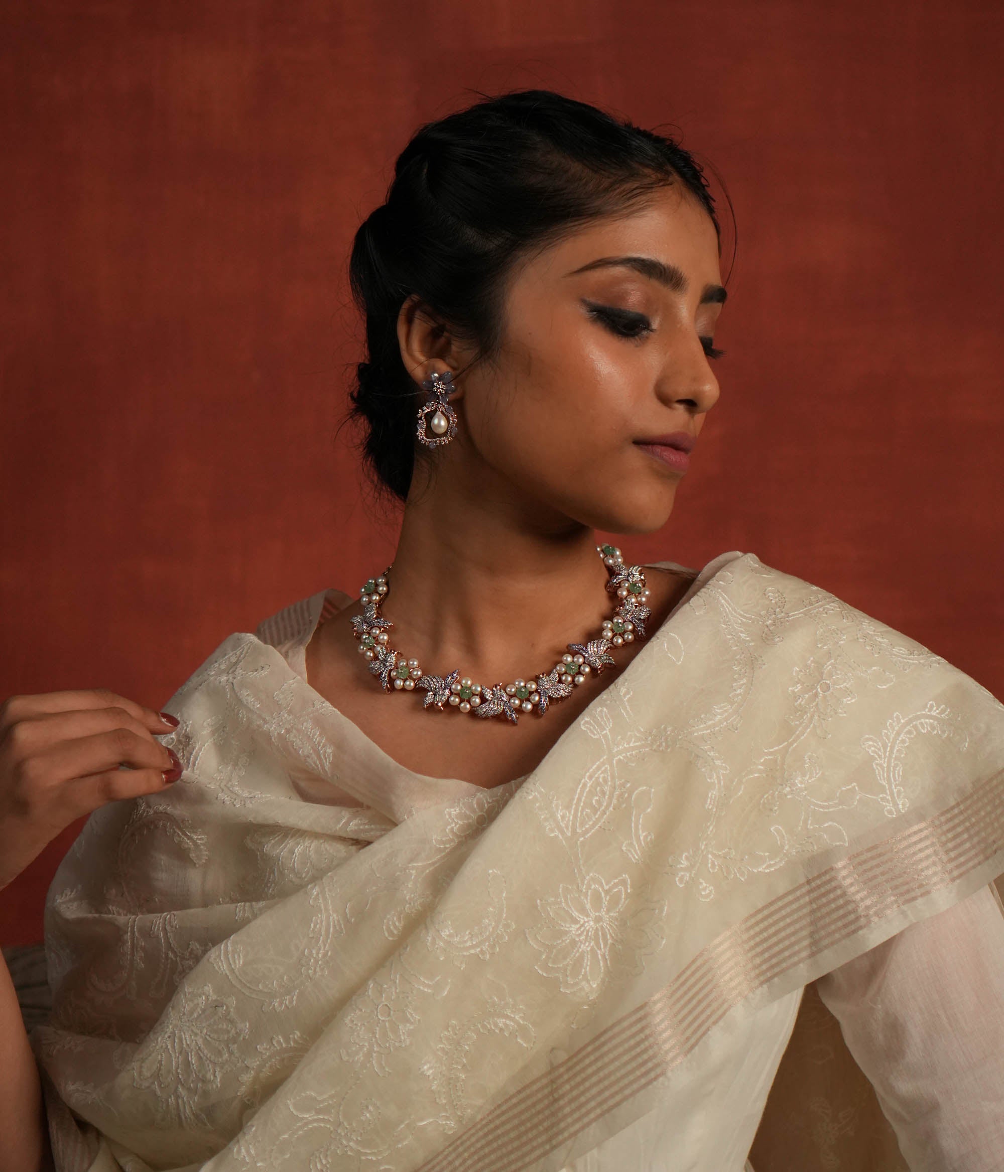 A stunning gold-plated silver necklace featuring an exquisite floral and bird design. The delicate flowers are crafted with lustrous pearls, while the intricately designed bird is adorned with shimmering CZ stones. The bird's eyes are highlighted with vibrant red spinel stones, adding a captivating touch. This elegant piece offers a unique and graceful finish, making it a timeless addition to any collection.