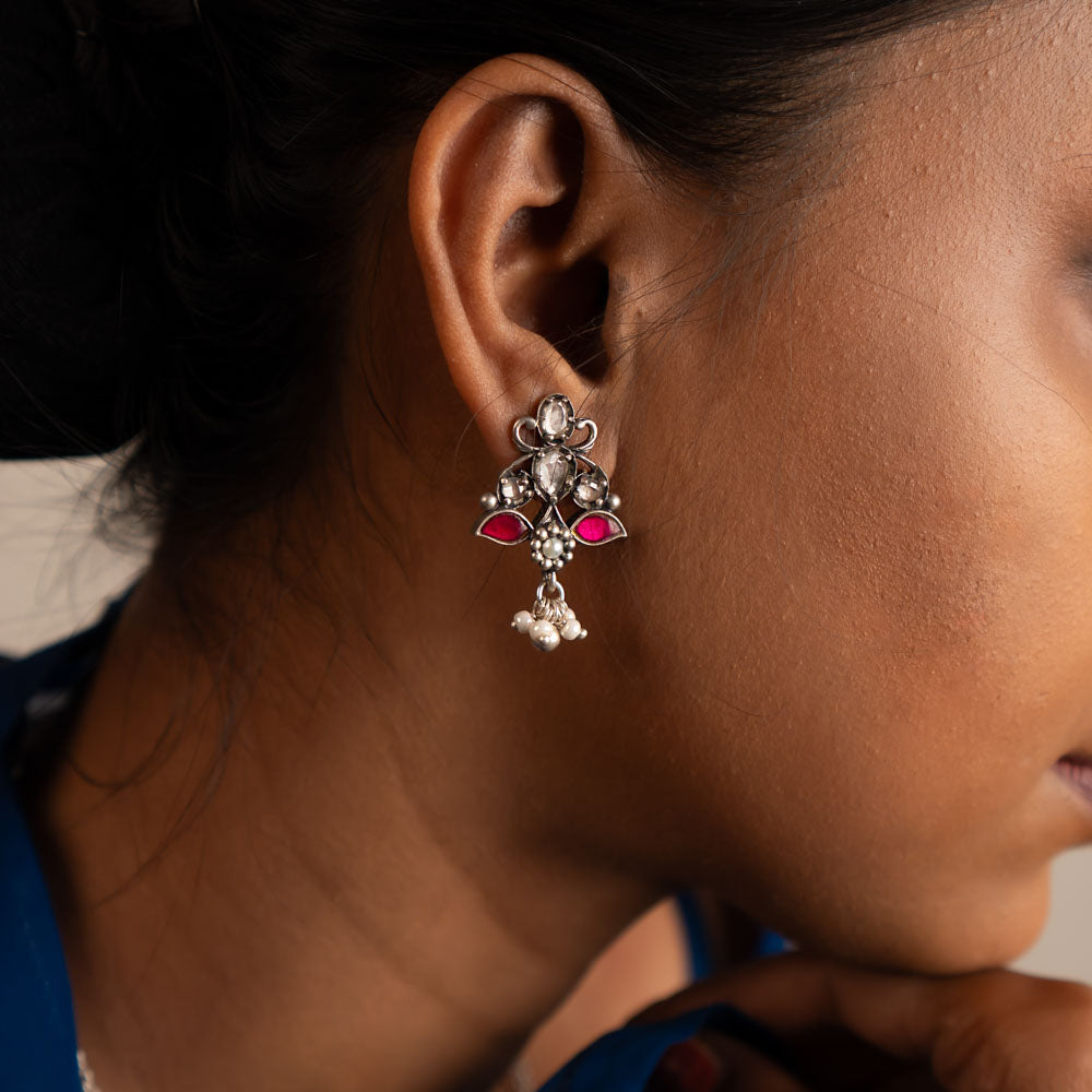 This oxidized silver drop earring features a stunning blend of red and white Kundan stones at its center, elegantly accented with freshwater pearl danglers for a timeless finish.