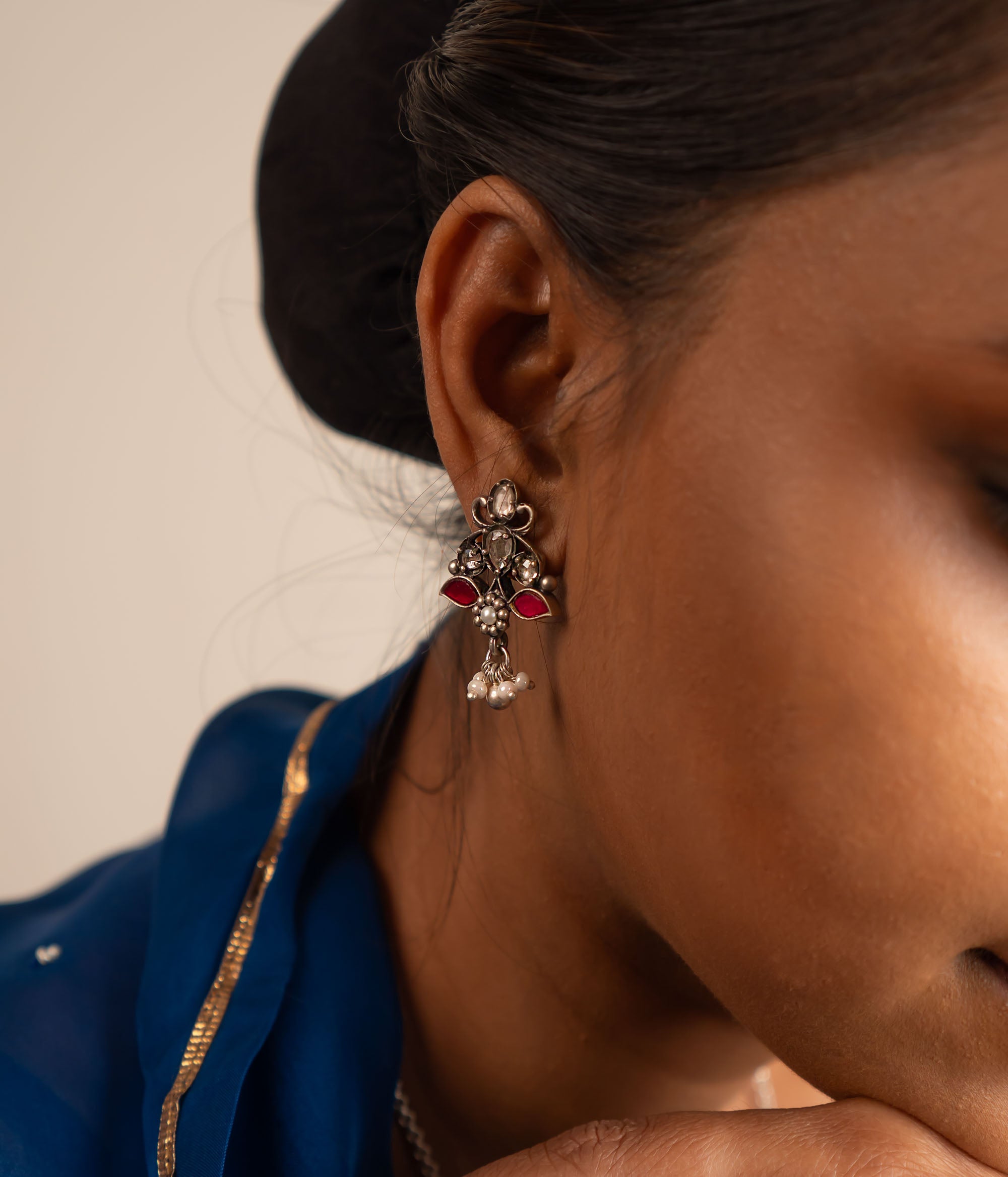 This oxidized silver drop earring features a stunning blend of red and white Kundan stones at its center, elegantly accented with freshwater pearl danglers for a timeless finish.