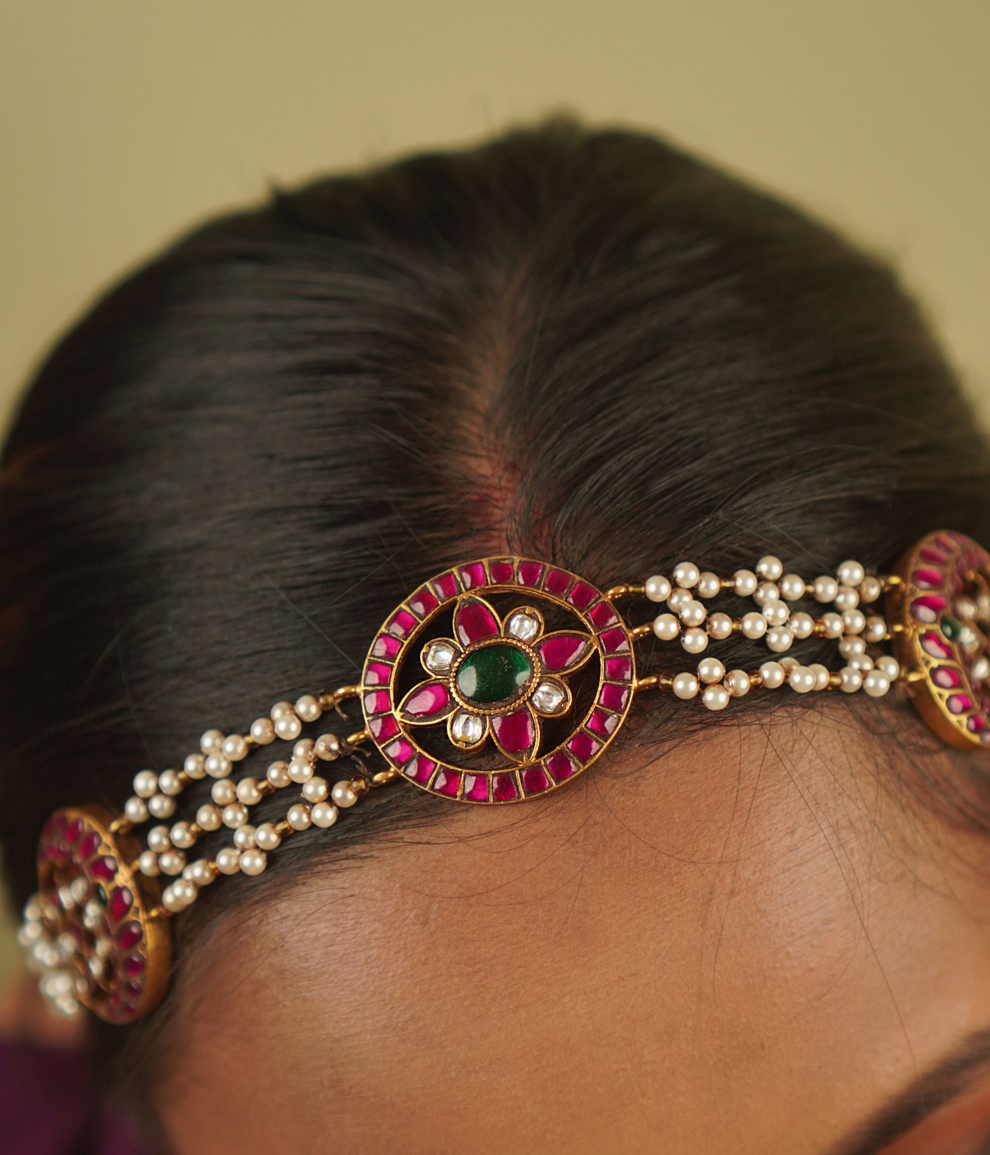 Sarayi Mathapatti: A graceful fusion of tradition and charm, featuring pearls and floral Kundan accents in red, white, and green, set in gold-plated silver—a piece that echoes timeless stories.