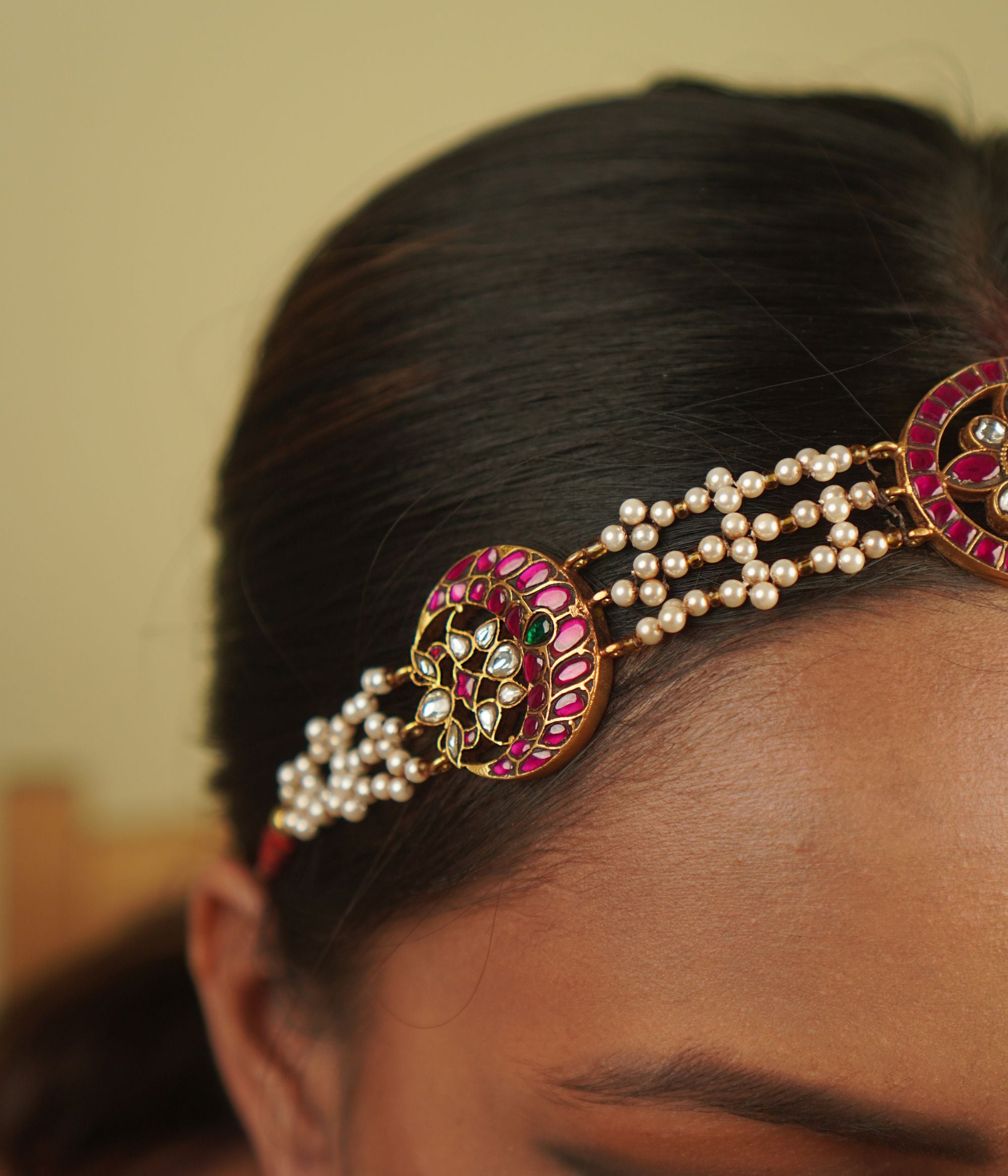 Sarayi Mathapatti: A graceful fusion of tradition and charm, featuring pearls and floral Kundan accents in red, white, and green, set in gold-plated silver—a piece that echoes timeless stories.