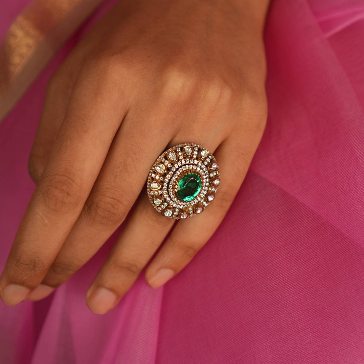 A Victorian-inspired Moissanite ring, featuring a mesmerizing green gemstone at its heart, radiates timeless elegance and sophistication with its halo of polki and CZ stones.