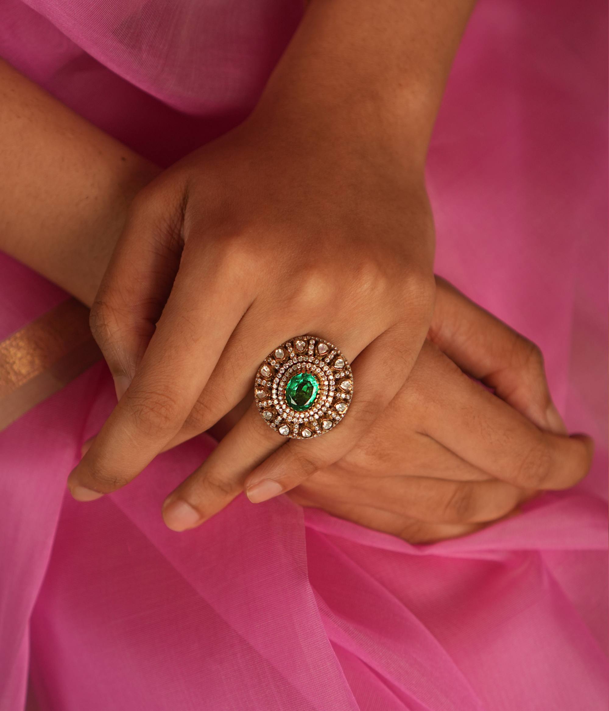 A Victorian-inspired Moissanite ring, featuring a mesmerizing green gemstone at its heart, radiates timeless elegance and sophistication with its halo of polki and CZ stones.