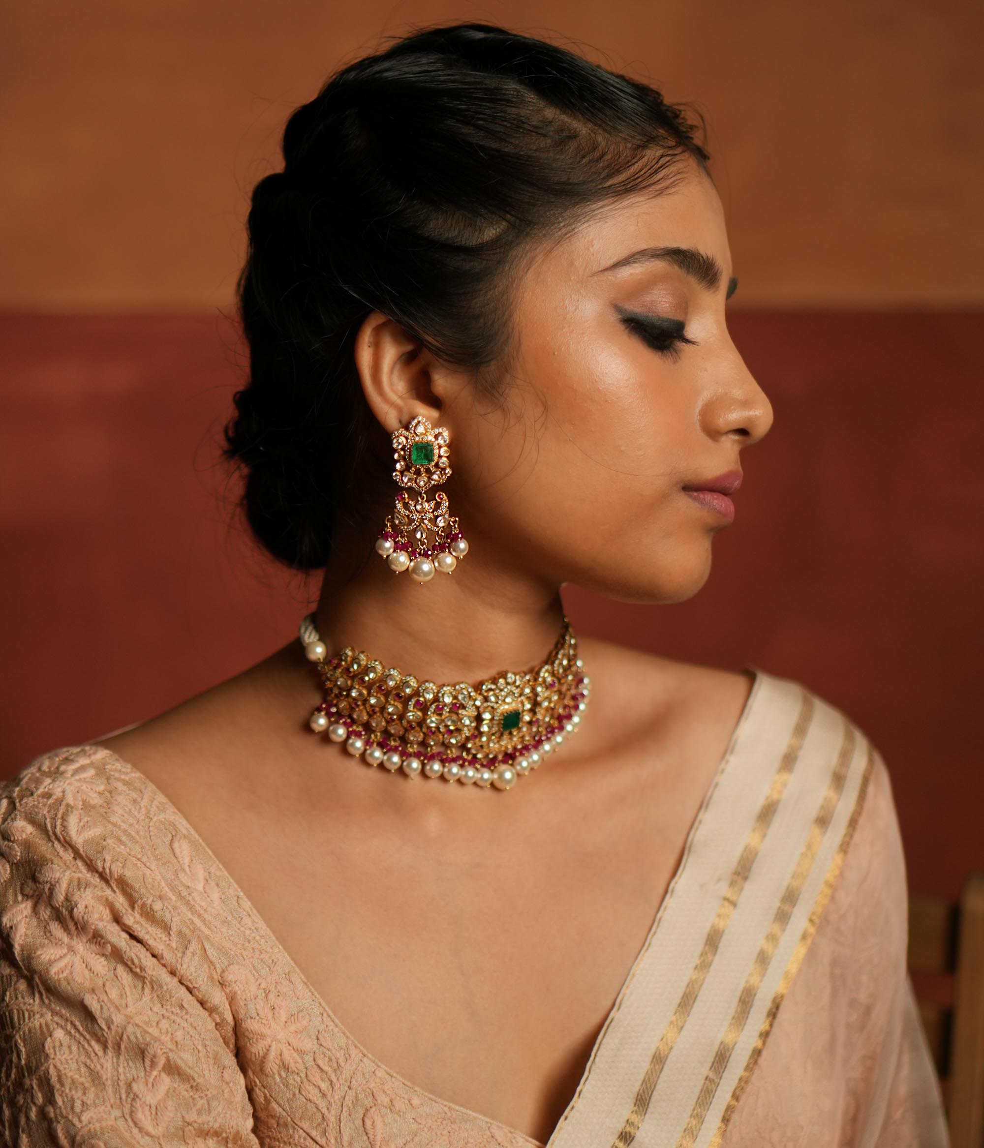 Elegant dangler earrings featuring a floral design adorned with Green Gemstone, Moissanite Polki Stones, Red Beads, Pearls, and CZ Stones. The earrings showcase a continuous arrangement of Polki and Red Beads, gracefully finished with delicate pearl drops for a sophisticated look.
