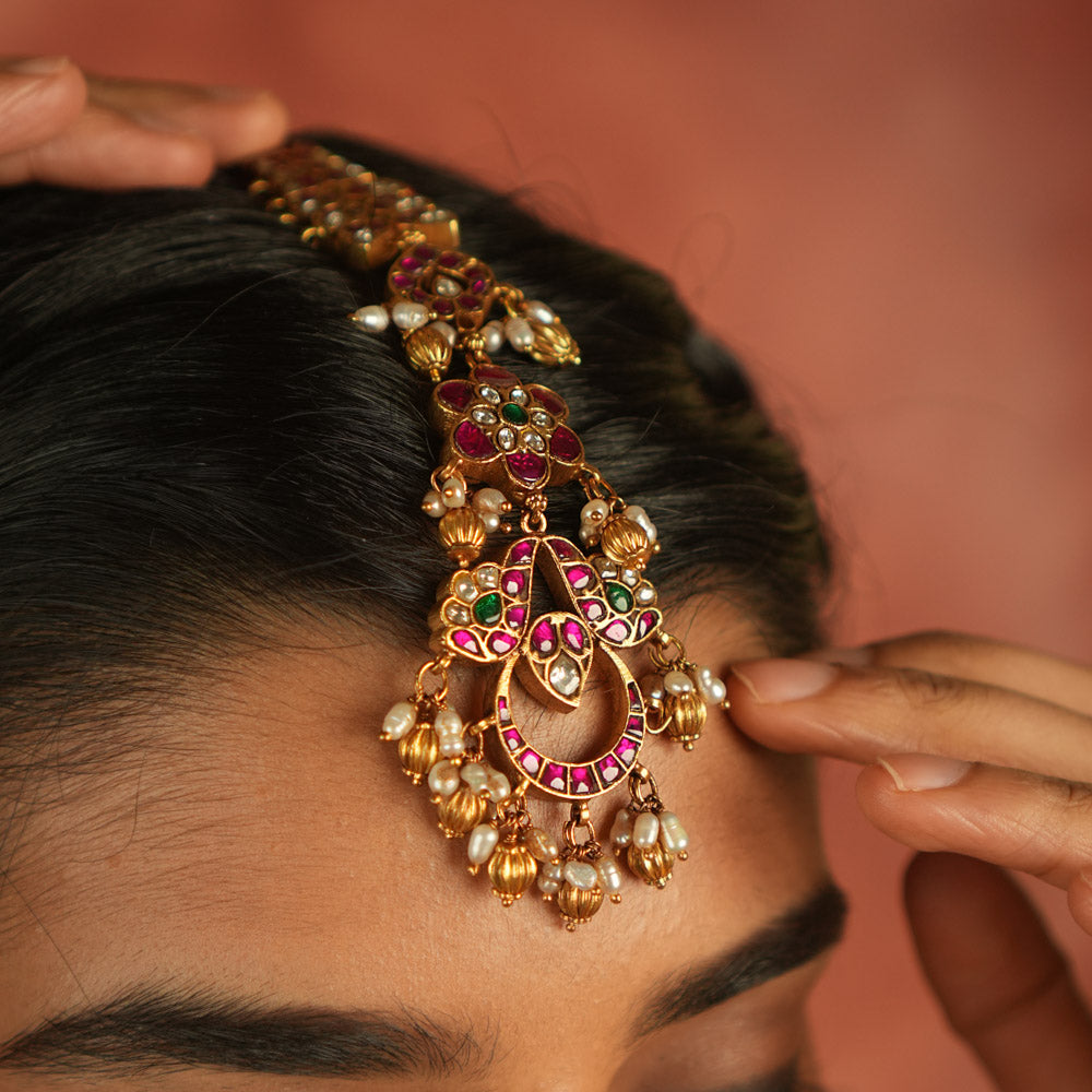 Ethereal bloom reborn! A floral Kundan maangtika adorned with pearls and red beads, where celestial grace meets timeless splendor.