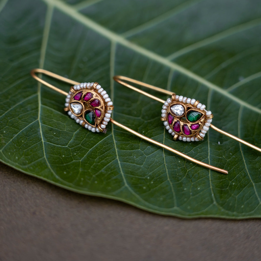 A handcrafted 92.5 sterling silver and 22ct gold-plated bugadi, featuring white, red, and green Kundan stones, pearls, and a delicate pearl border, reflecting timeless grace and artisanal craftsmanship.