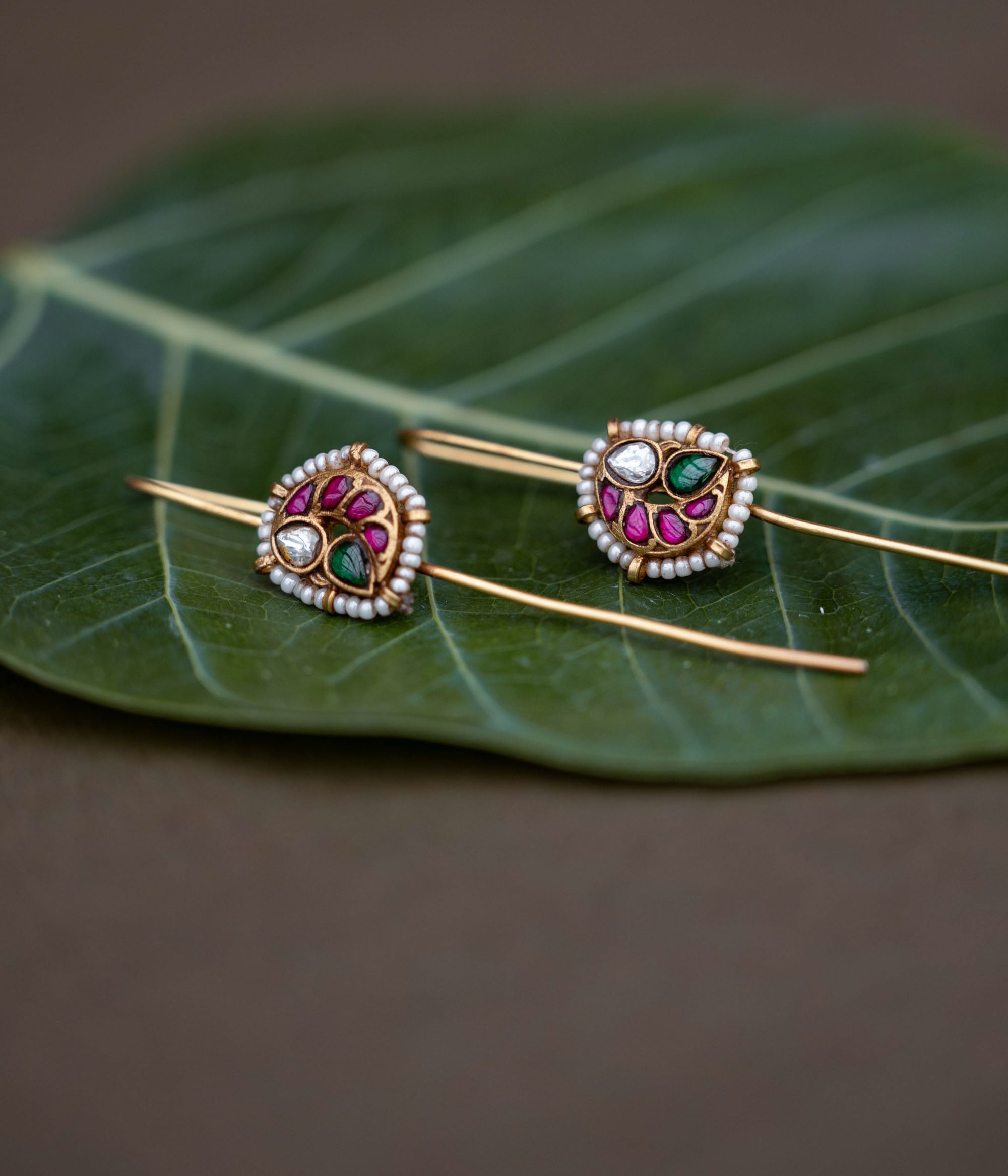 A handcrafted 92.5 sterling silver and 22ct gold-plated bugadi, featuring white, red, and green Kundan stones, pearls, and a delicate pearl border, reflecting timeless grace and artisanal craftsmanship.