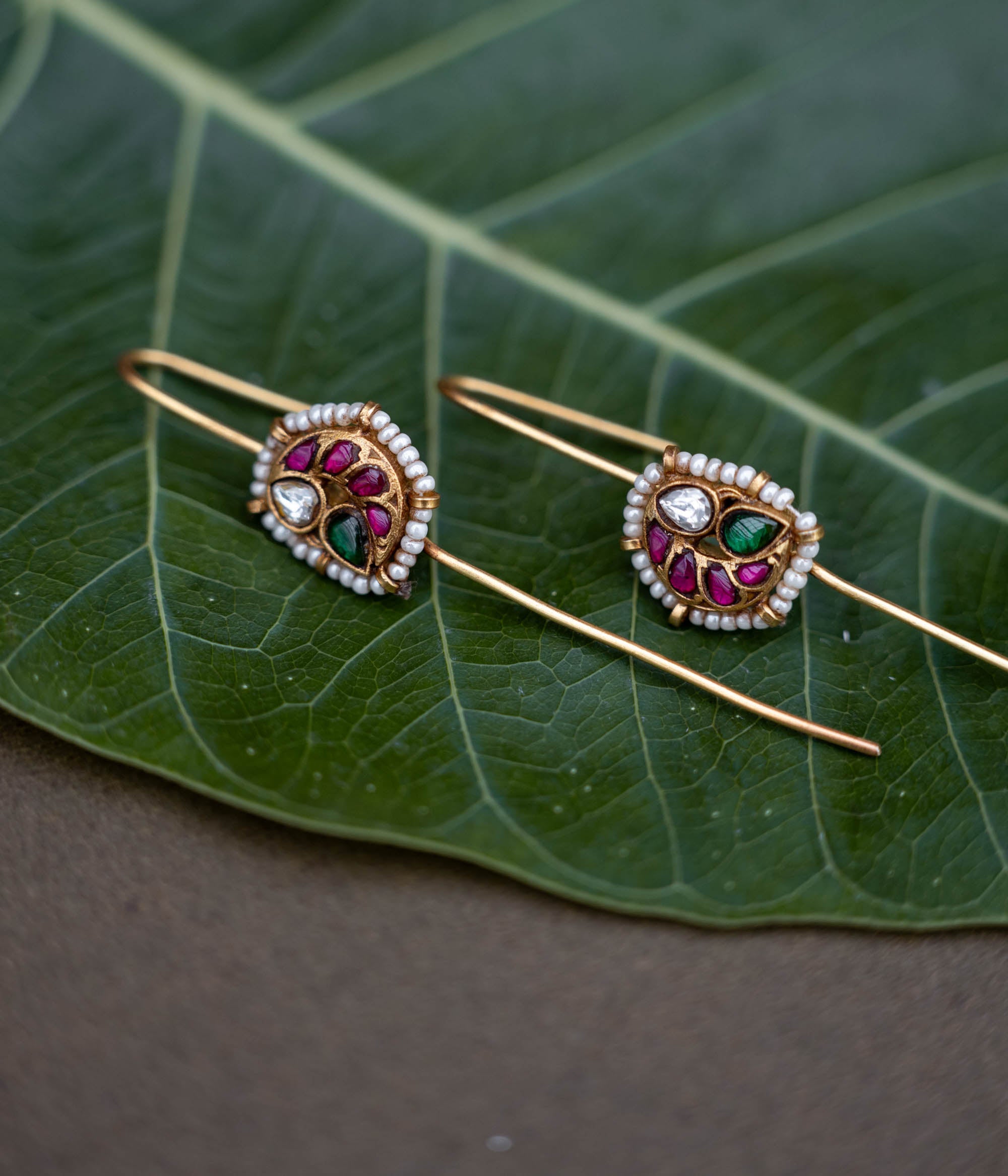 A handcrafted 92.5 sterling silver and 22ct gold-plated bugadi, featuring white, red, and green Kundan stones, pearls, and a delicate pearl border, reflecting timeless grace and artisanal craftsmanship.