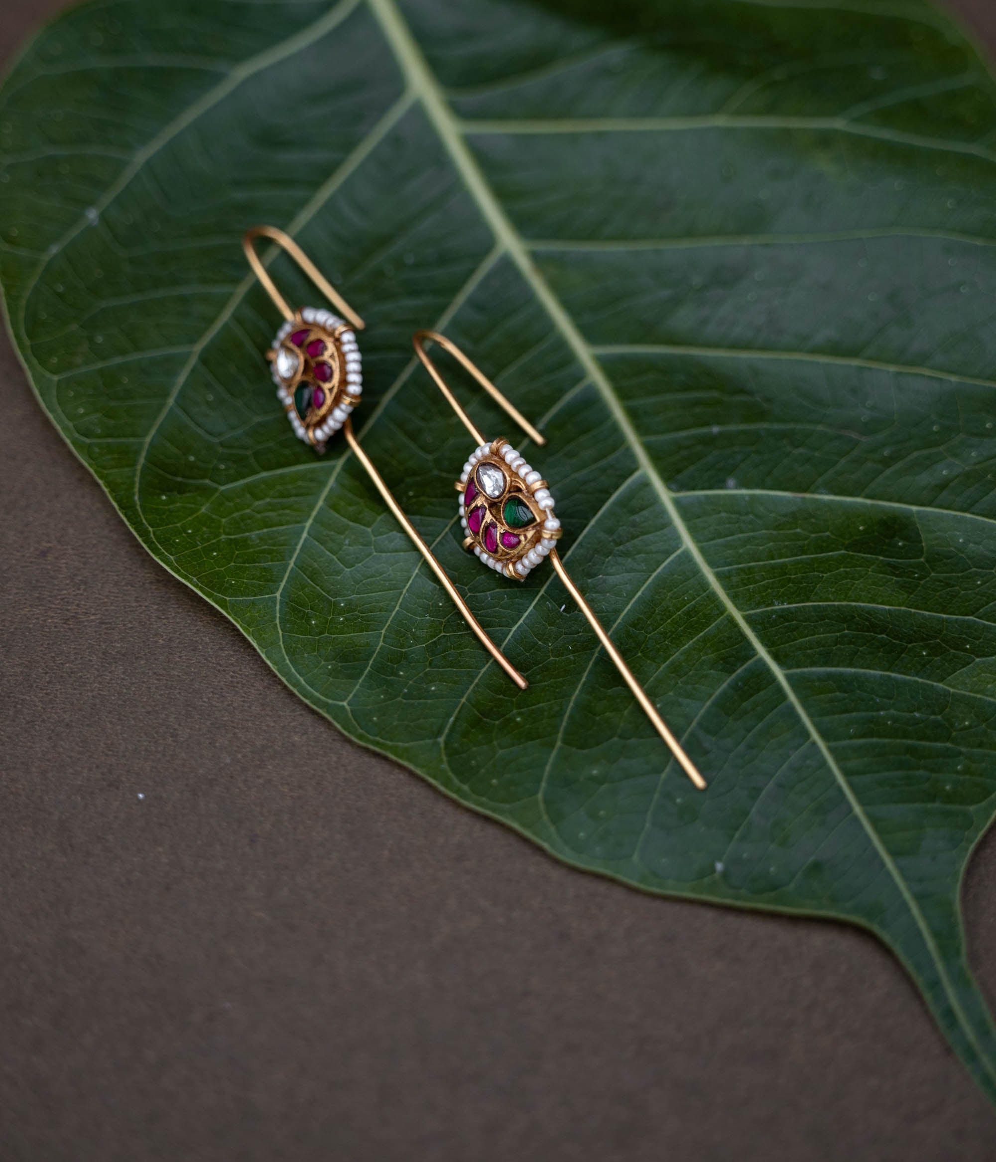 A handcrafted 92.5 sterling silver and 22ct gold-plated bugadi, featuring white, red, and green Kundan stones, pearls, and a delicate pearl border, reflecting timeless grace and artisanal craftsmanship.