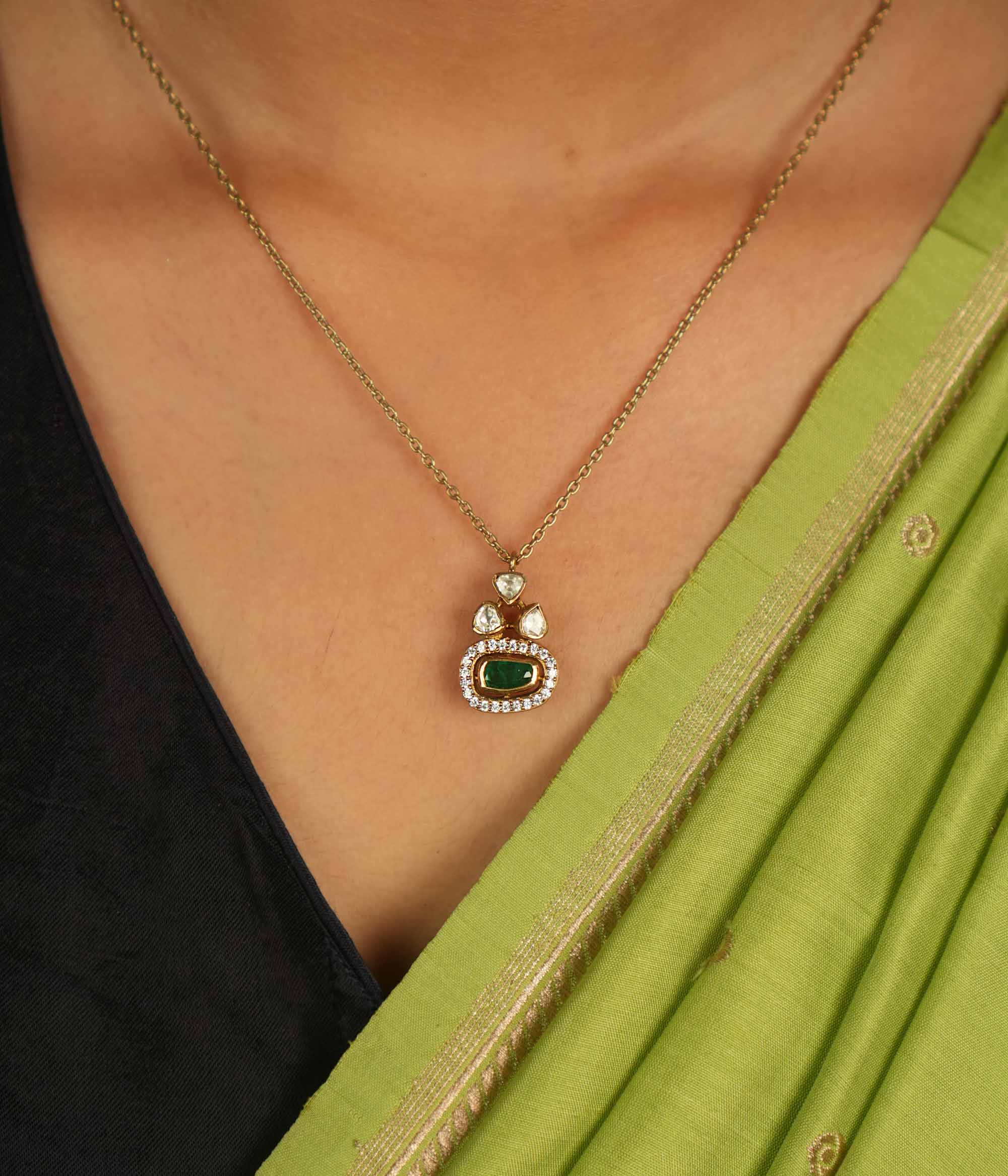 Geometric elegance redefined! This gold-plated silver pendant features an oval green gemstone at its heart, embraced by shimmering Moissanite Polki and CZ stones. A seamless blend of modern luxury and timeless charm.