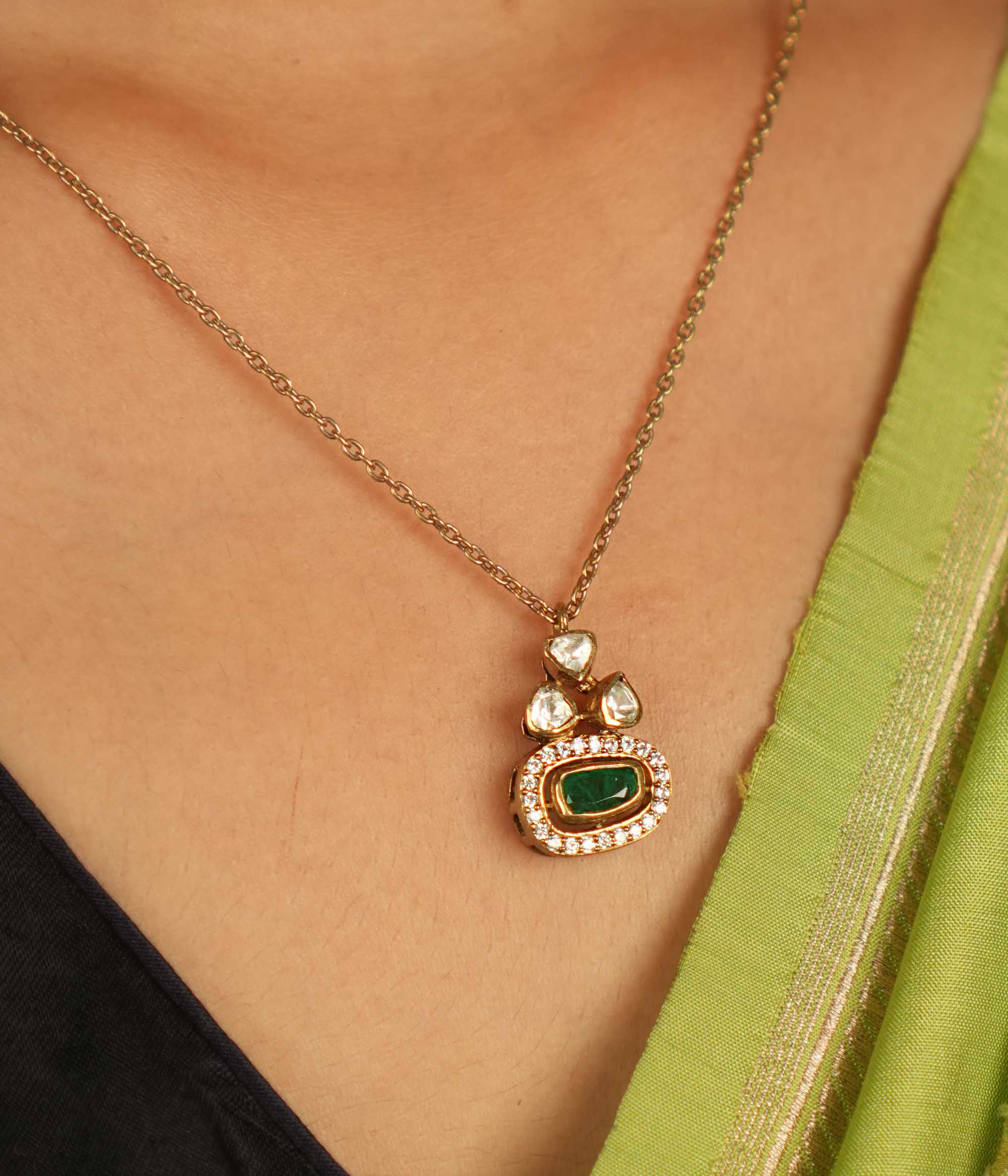 Geometric elegance redefined! This gold-plated silver pendant features an oval green gemstone at its heart, embraced by shimmering Moissanite Polki and CZ stones. A seamless blend of modern luxury and timeless charm.