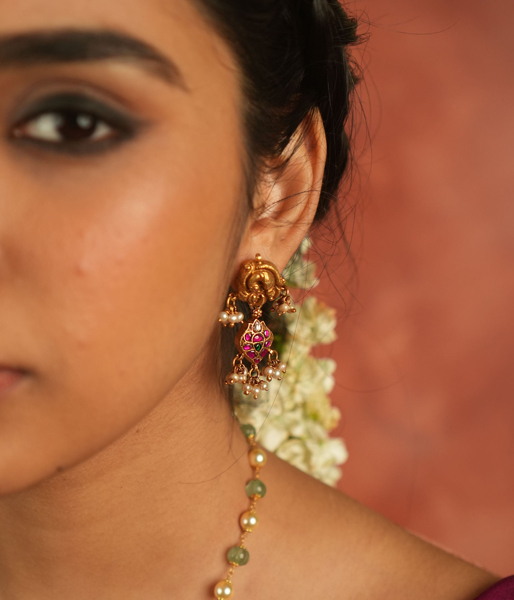 Bazaar whispers reborn! Kundan peacock dangler earrings with pearl droplets dance in harmony with vibrant gems, crafting a symphony of elegance.