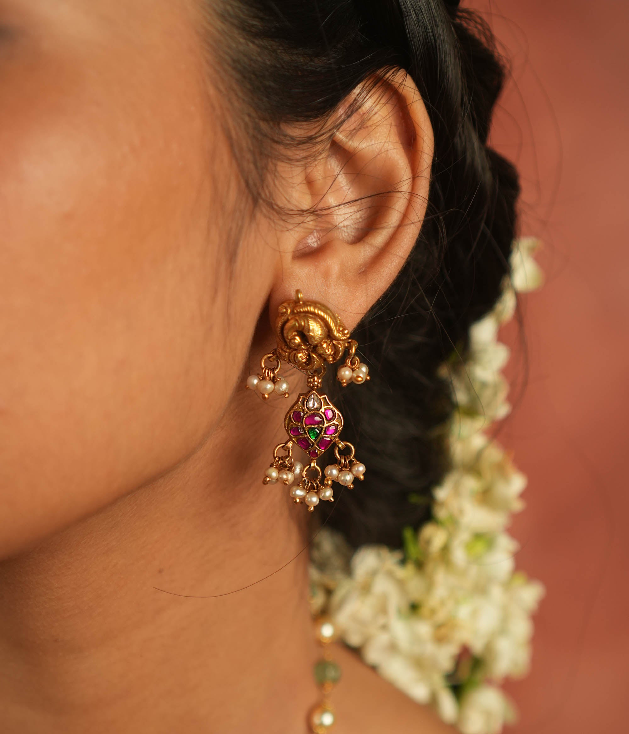 Bazaar whispers reborn! Kundan peacock dangler earrings with pearl droplets dance in harmony with vibrant gems, crafting a symphony of elegance.