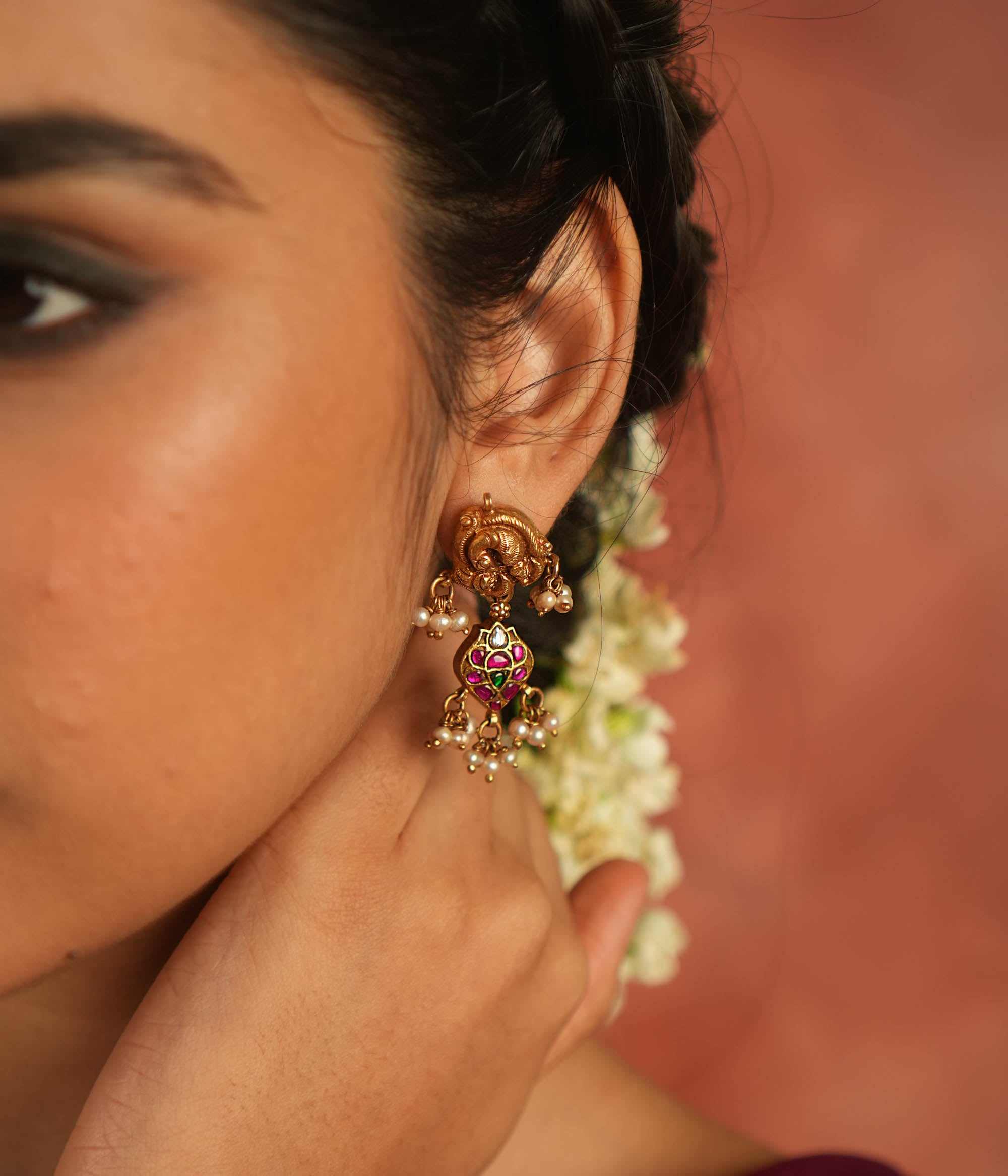 Bazaar whispers reborn! Kundan peacock dangler earrings with pearl droplets dance in harmony with vibrant gems, crafting a symphony of elegance.