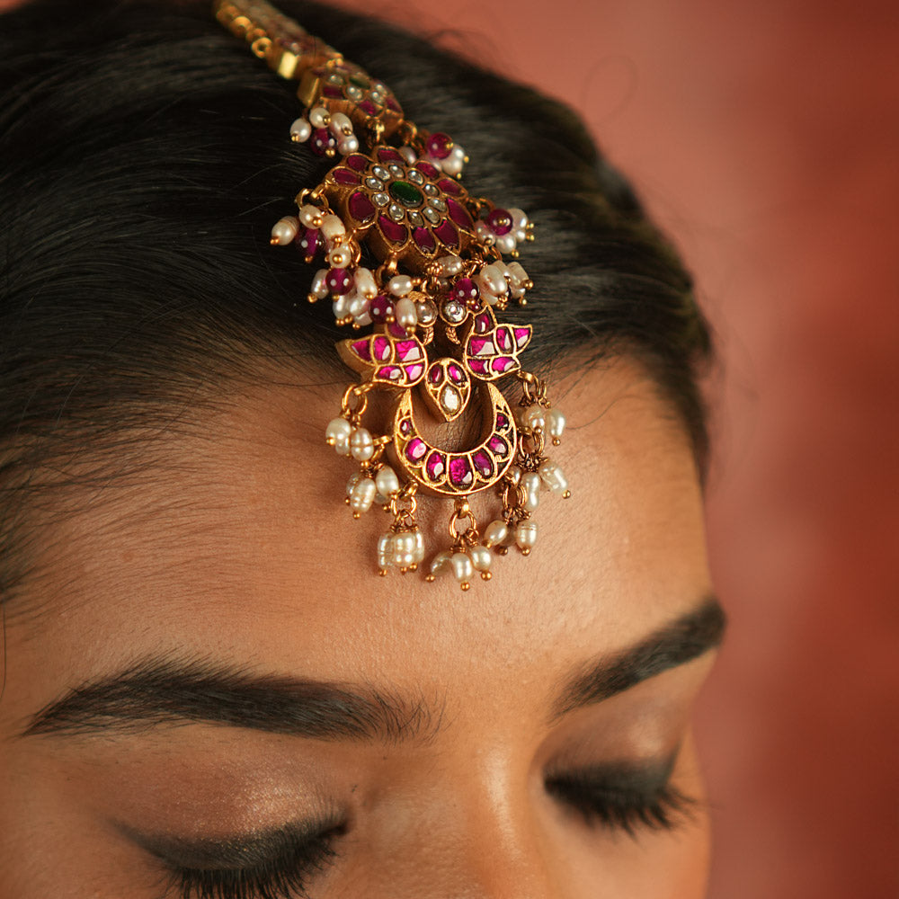 Ethereal bloom reborn! A floral Kundan maangtika adorned with pearls and red beads, where celestial grace meets timeless splendor.