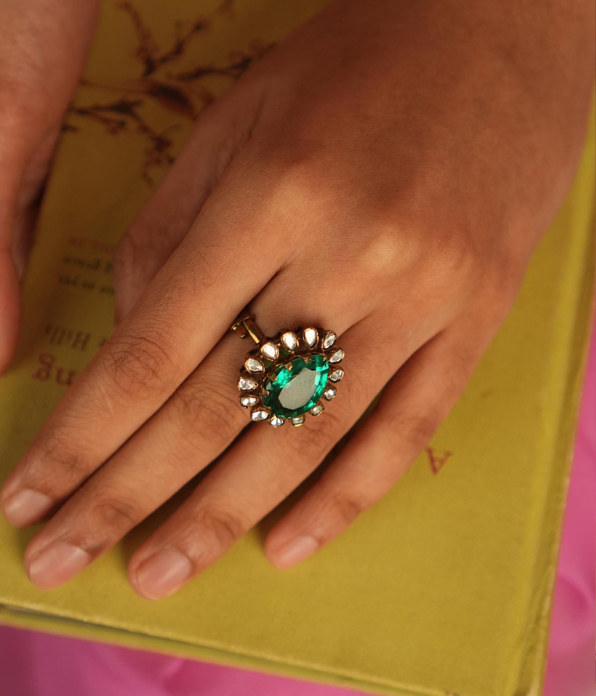 A teardrop ring featuring a vivid green gemstone, encircled by shimmering Polki and CZ stones, where each facet sparkles with celestial brilliance, echoing timeless elegance.