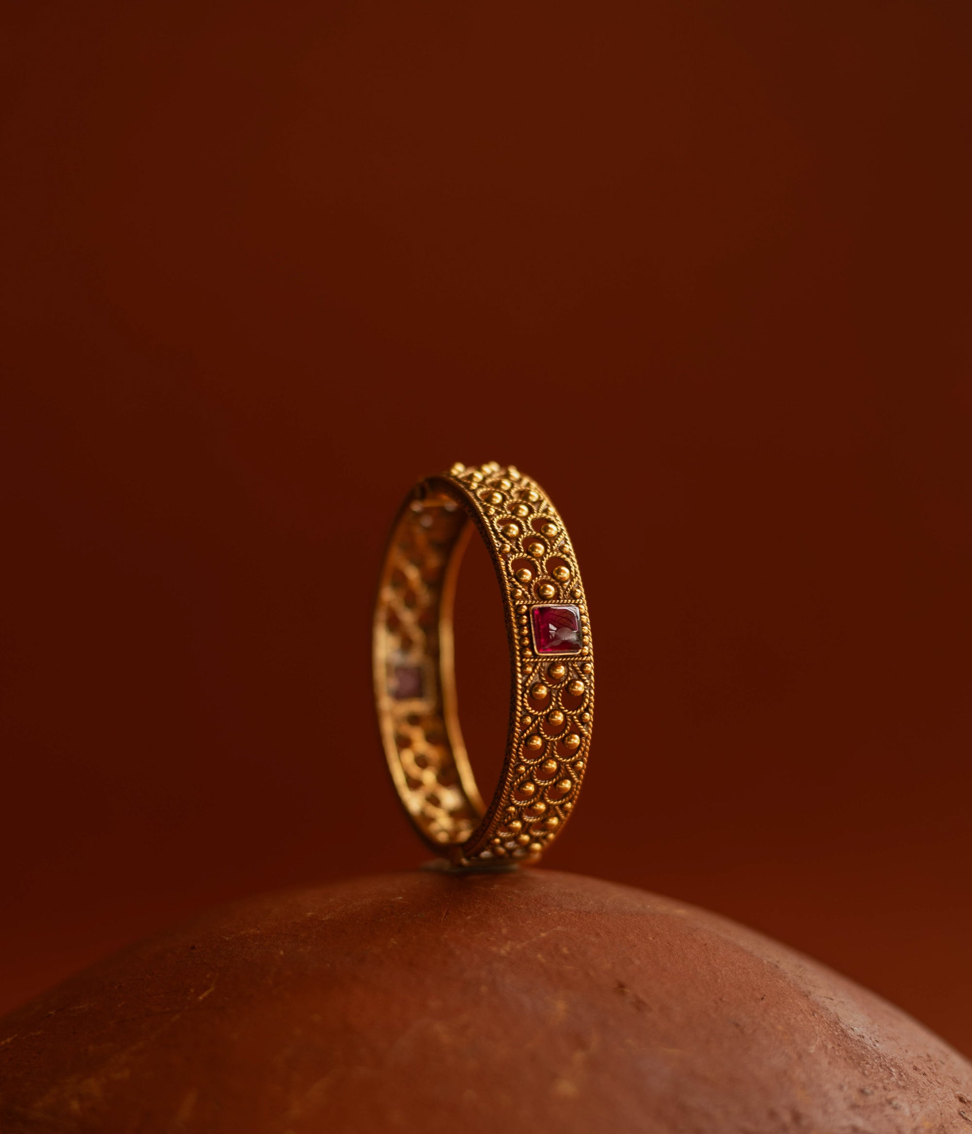 Tribal bangle with red spinal stones and feather-inspired design motifs.