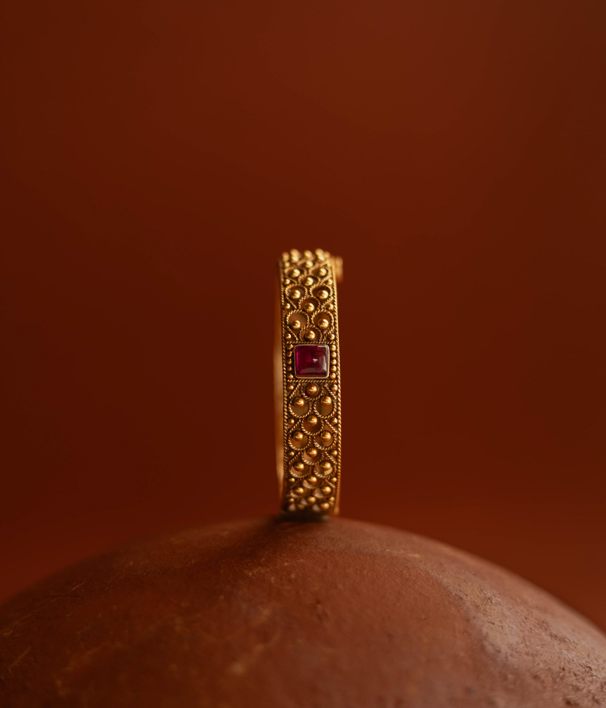 Tribal bangle with red spinal stones and feather-inspired design motifs.