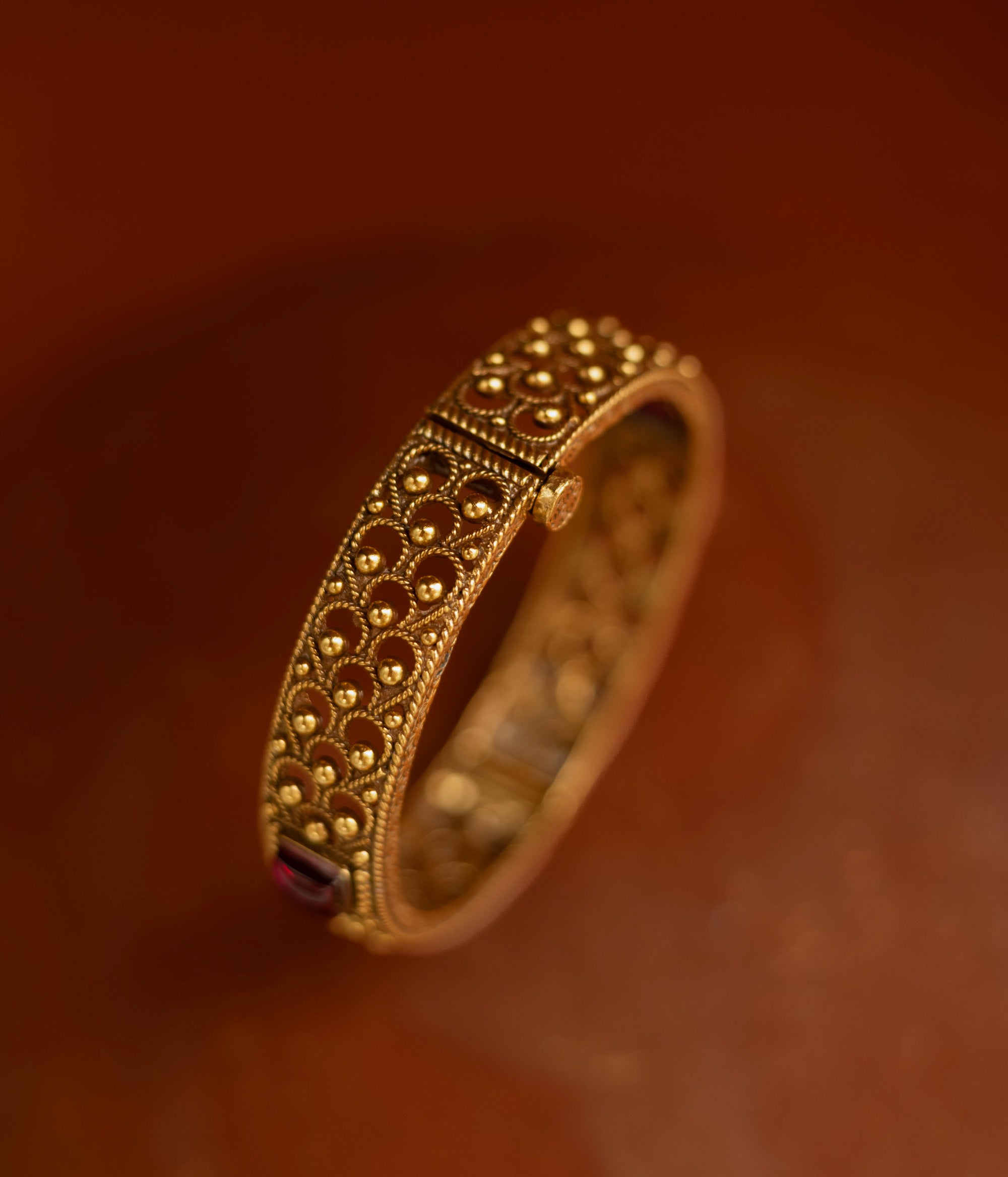 Tribal bangle with red spinal stones and feather-inspired design motifs.