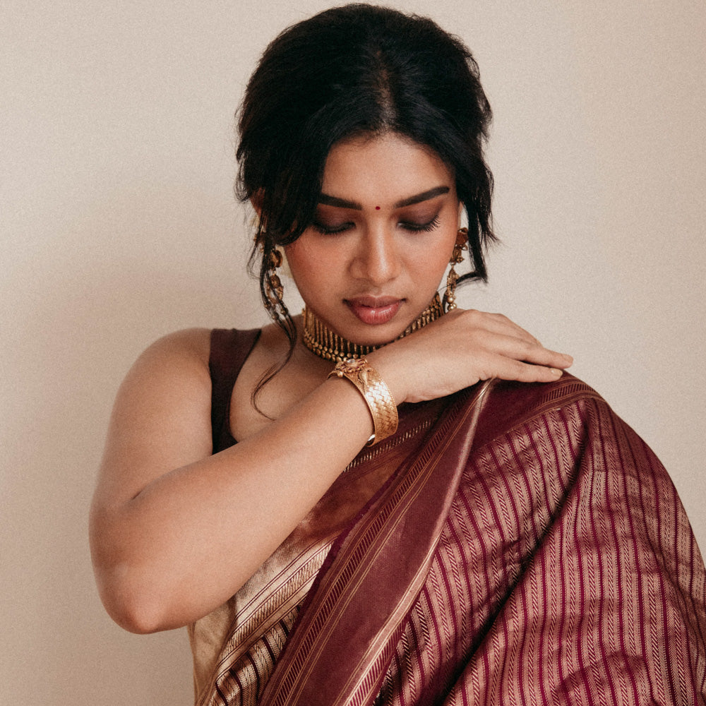 Antique gold tribal bangle with Red Spinal and White Kundan stones worn by model in saree.
