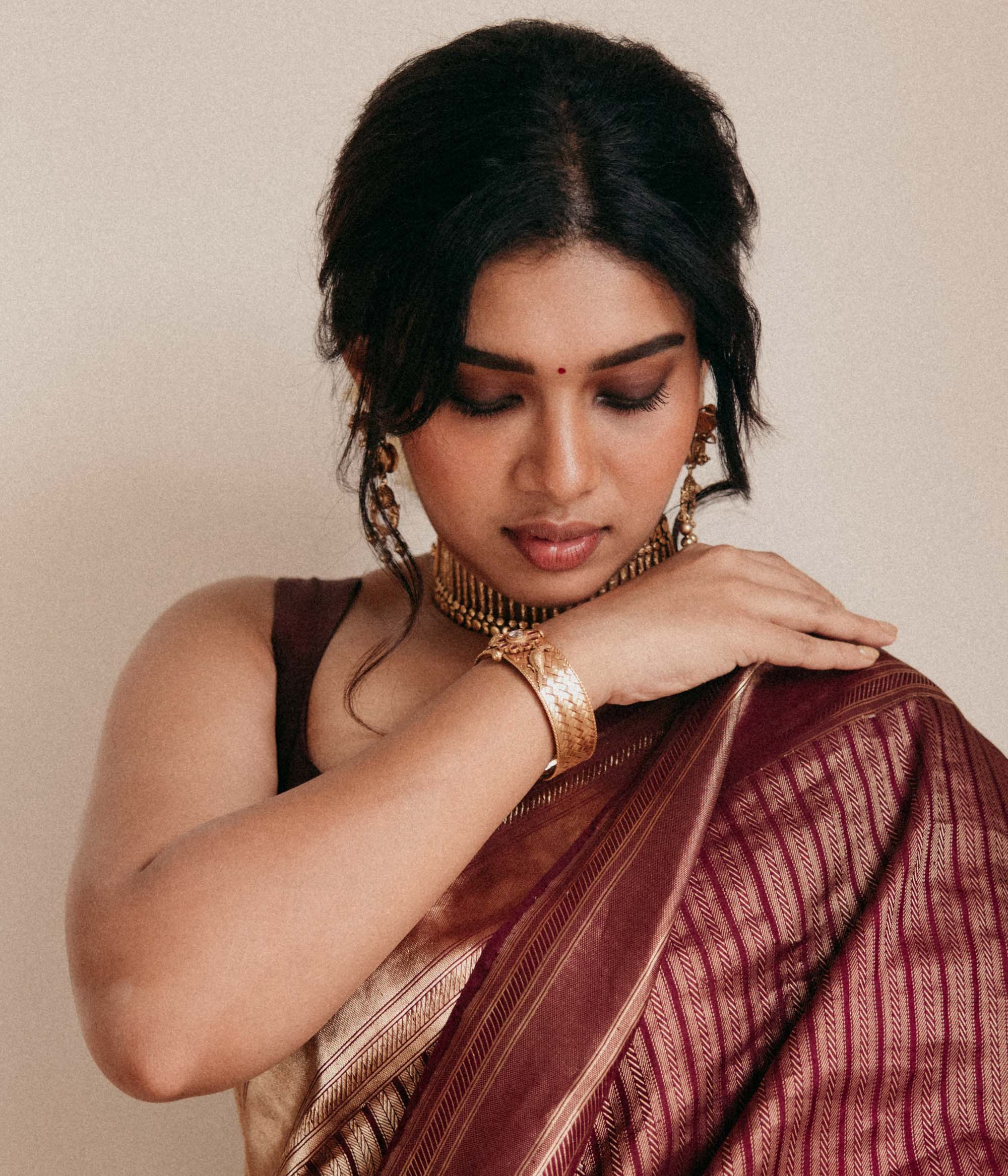 Antique gold tribal bangle with Red Spinal and White Kundan stones worn by model in saree.