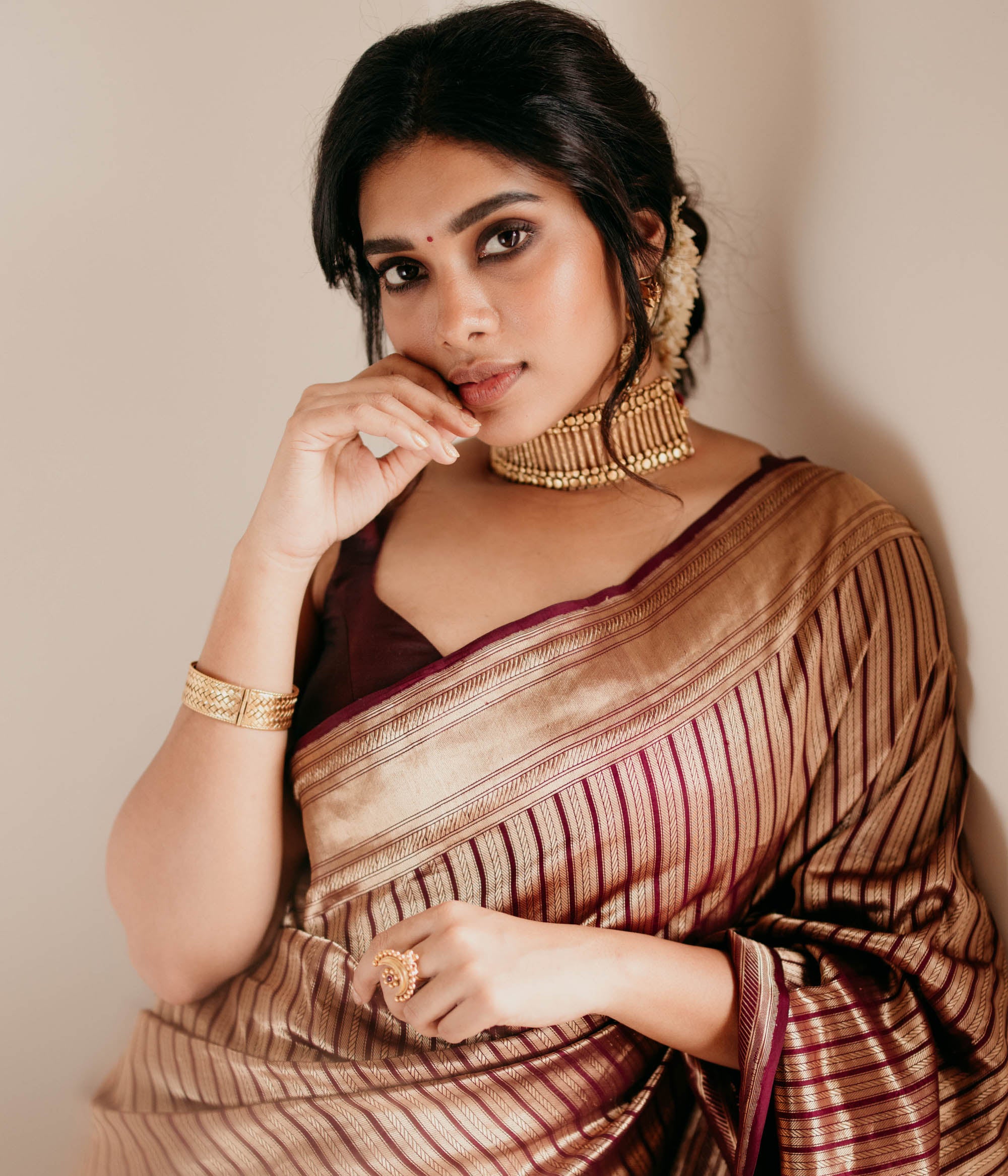 Bold tribal gold choker with vertical bar design and bead detailing, worn with maroon saree.