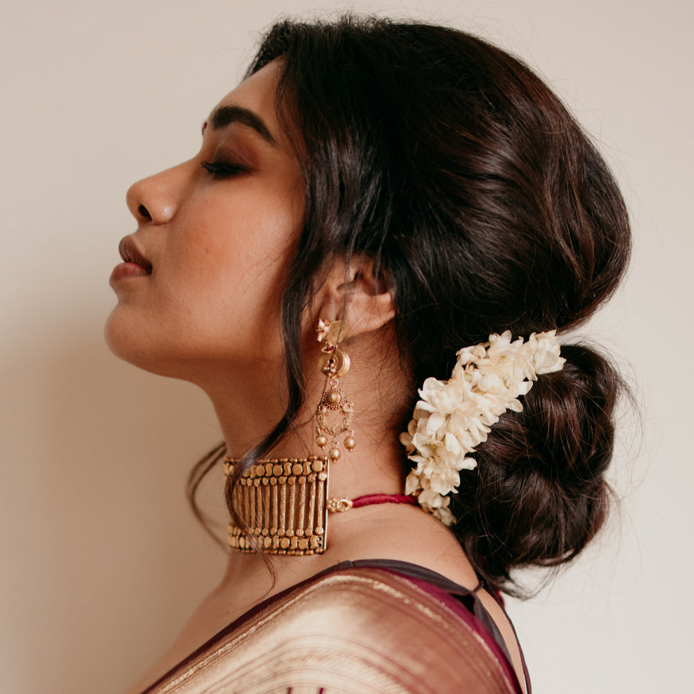 Gold tribal earrings with dangling design and Red Spinal Stones, styled with traditional jasmine hairdo.